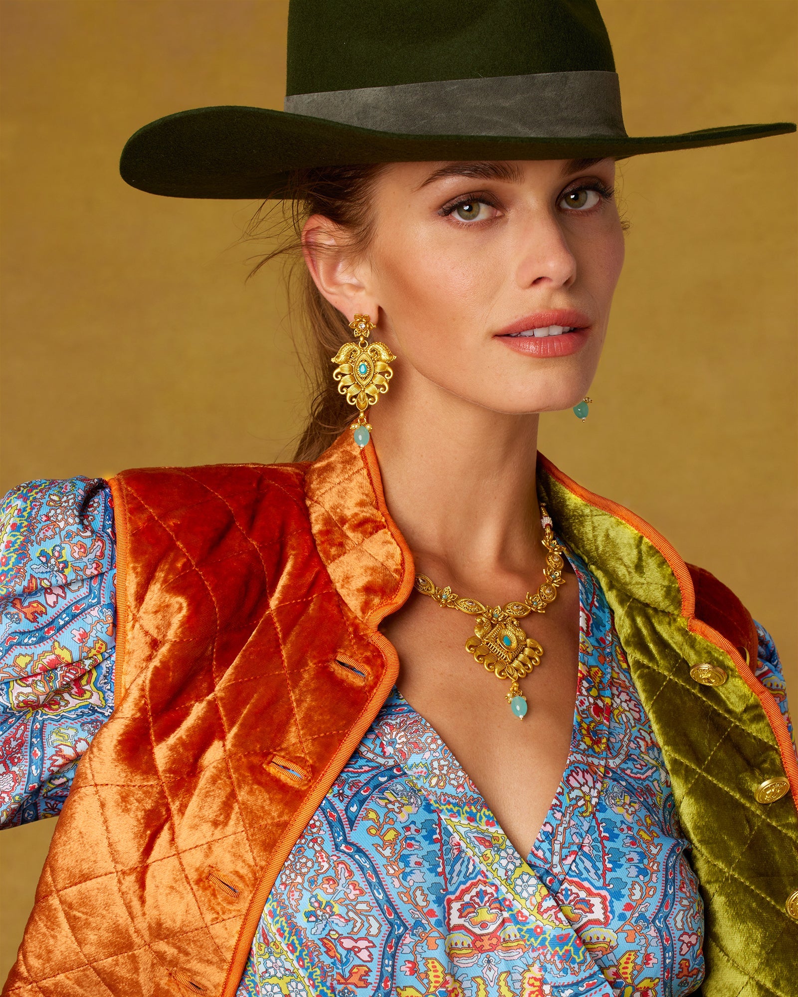 Nawal Earrings in Gold Pated Filigree and Aquamarine-Worn with Velvet Quilted Vest and Midi Wrap Dress