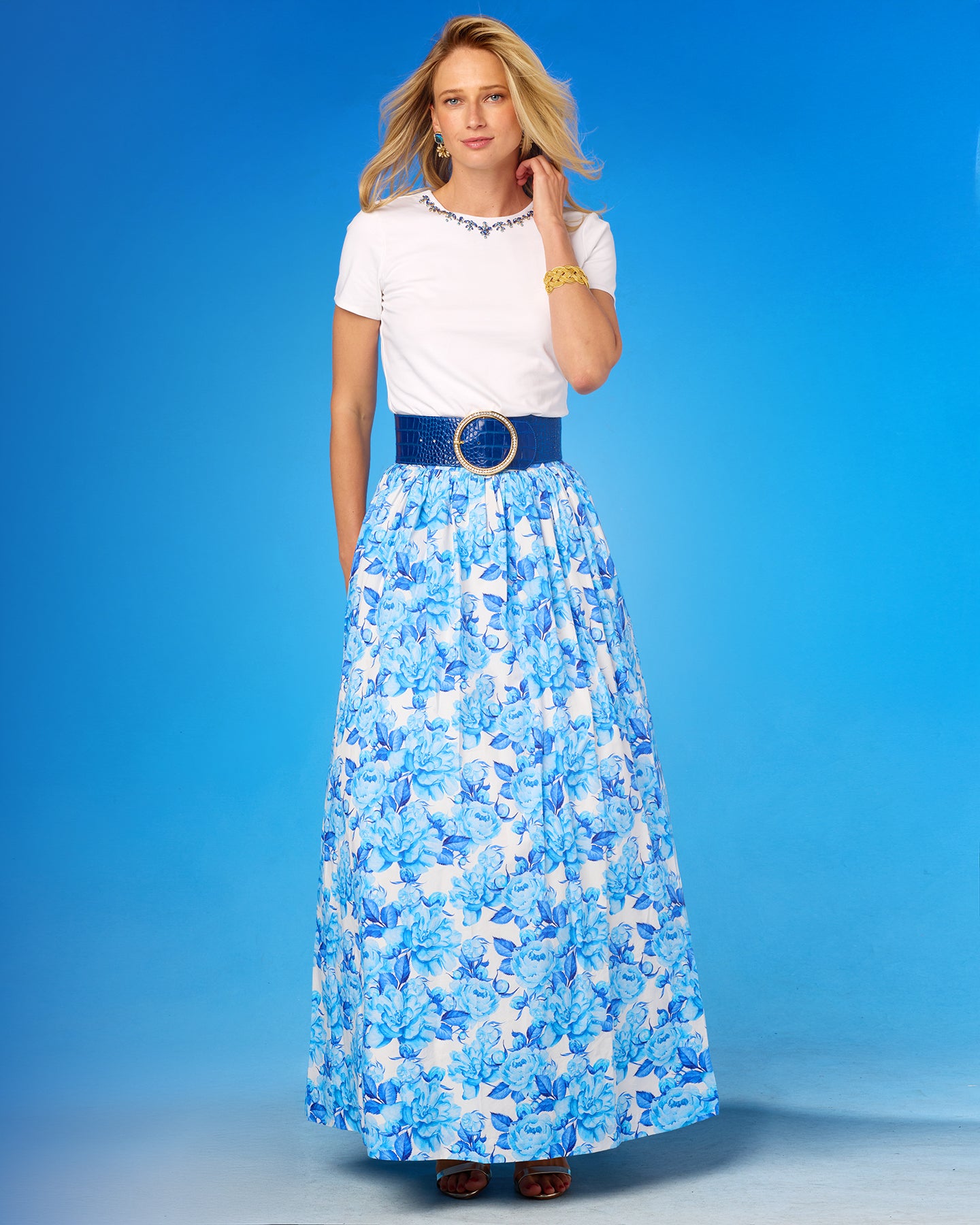 Woman wearing a white top and blue floral skirt against a blue background