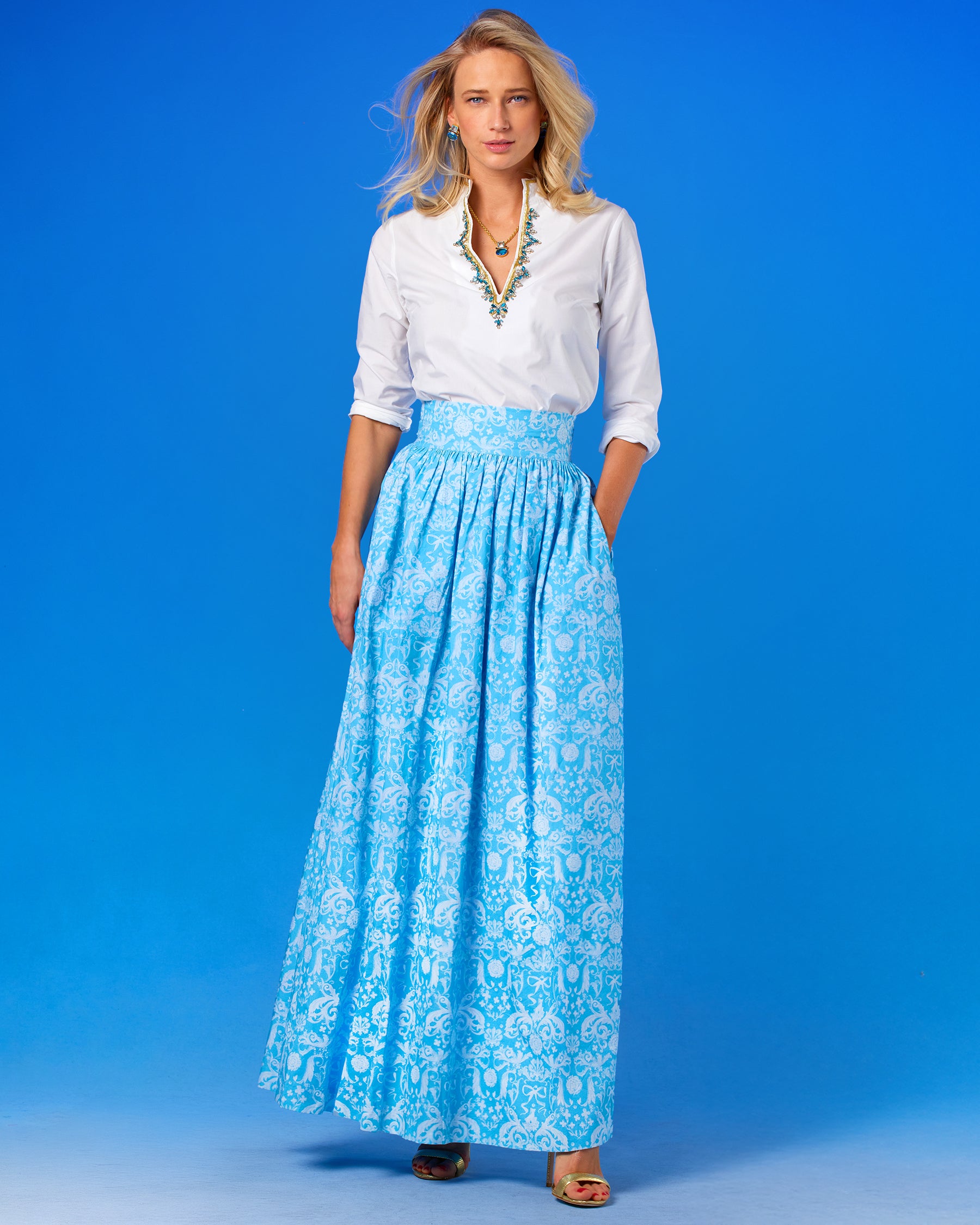 Alexandra Long Full Skirt in Porcelain Regency Ribbons worn with the Circe Tunic in Pure White with Crystals and Gold Embellishment front view with hand in pocket