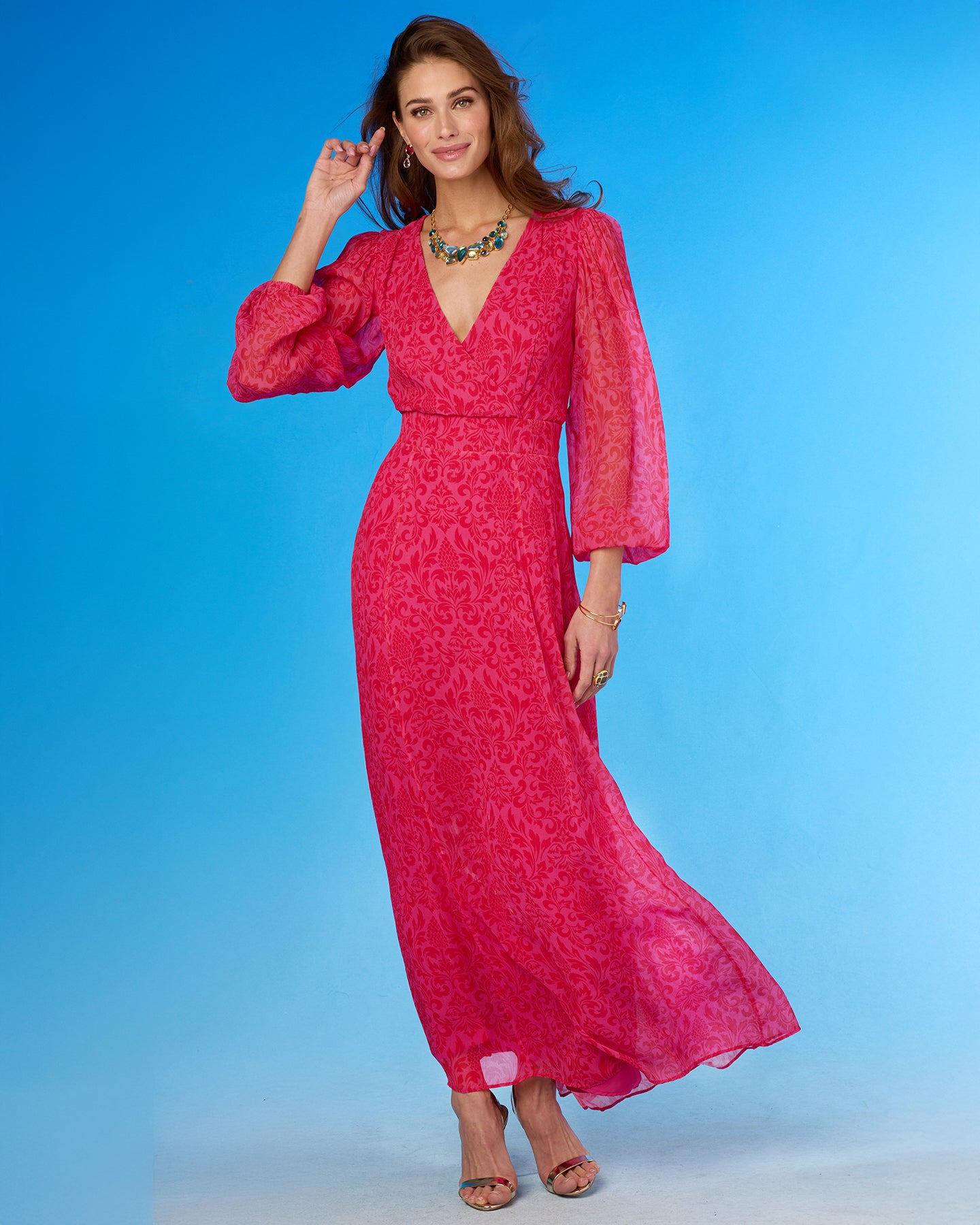 Woman wearing a pink dress with long sleeves against a blue background