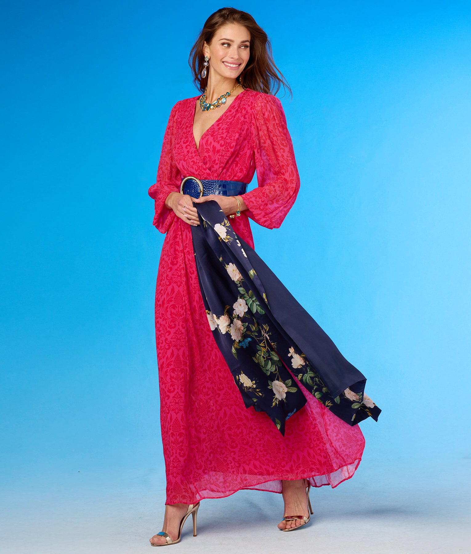 Woman wearing a pink dress with a floral scarf against a blue background