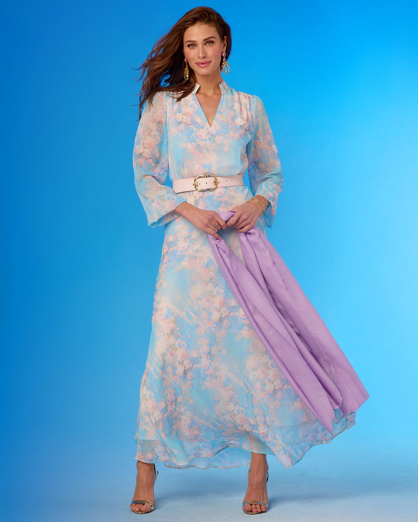 Woman wearing a floral dress with a purple scarf against a blue background