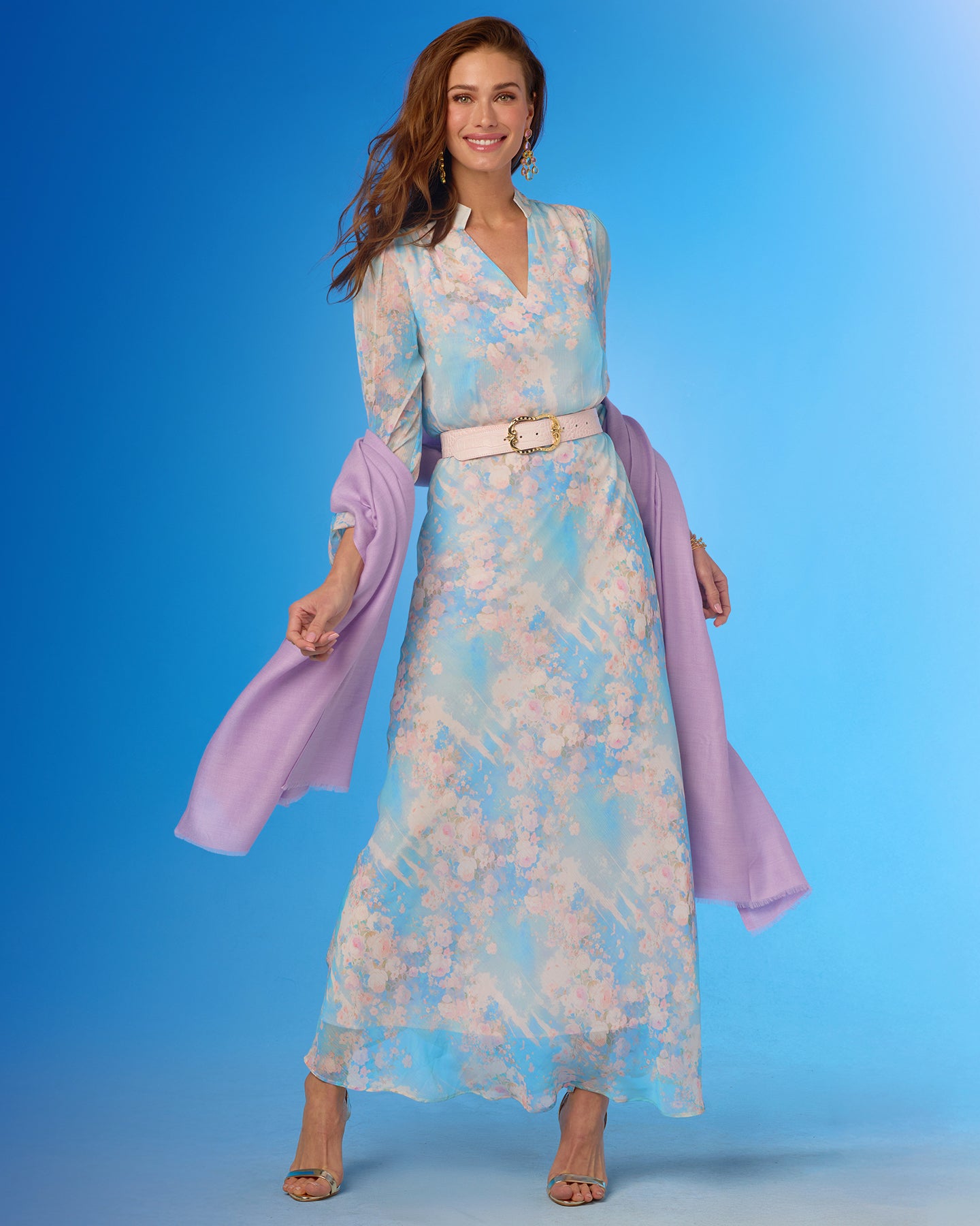 Woman wearing a floral dress with a pink shawl against a blue background