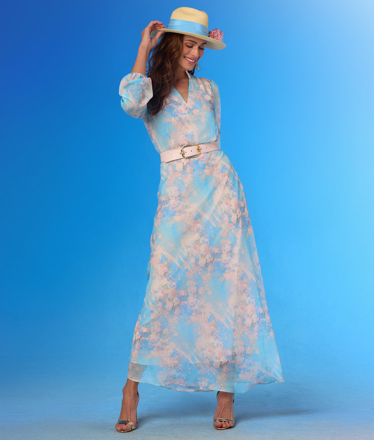 Woman wearing a floral dress and hat against a blue background