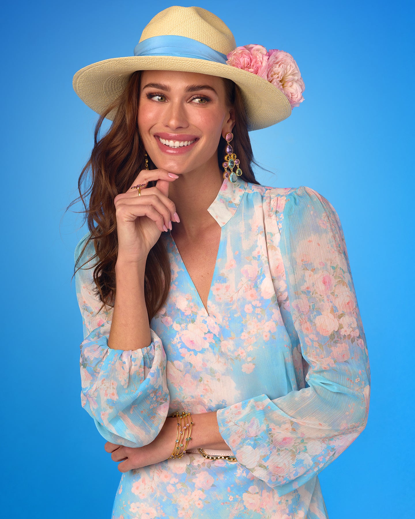 Woman wearing a floral dress and sun hat against a blue background