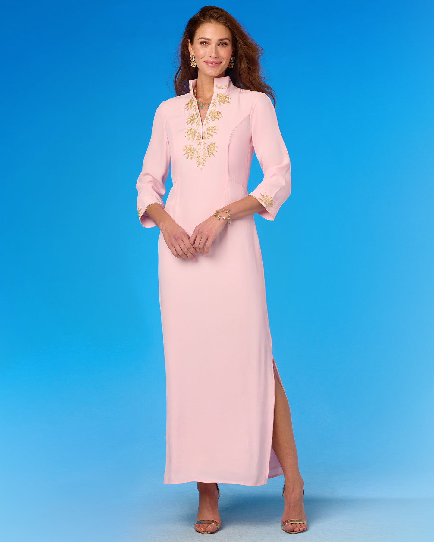 Woman wearing a pink dress with gold embroidery on a blue background