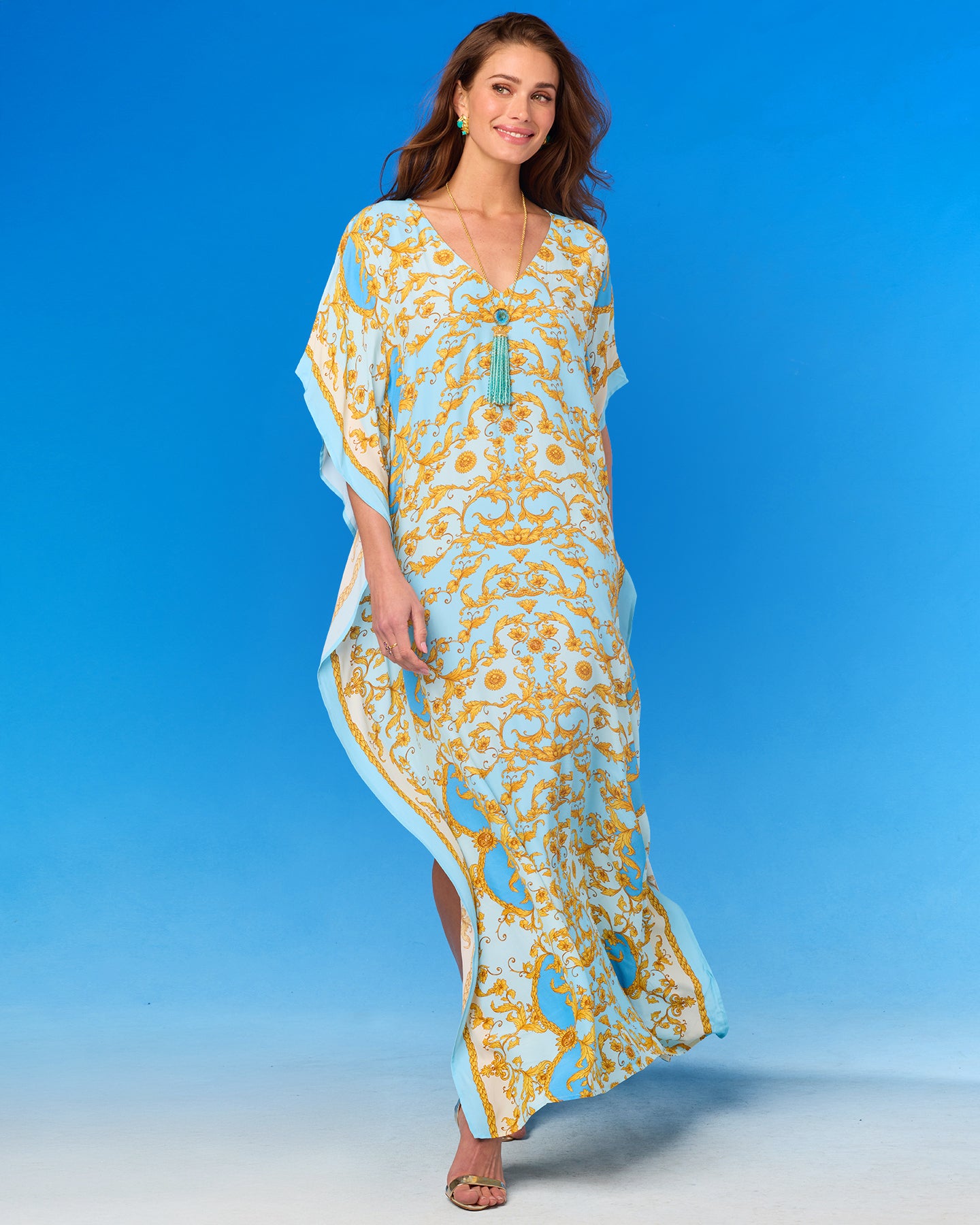 Woman wearing a long, patterned dress against a blue background