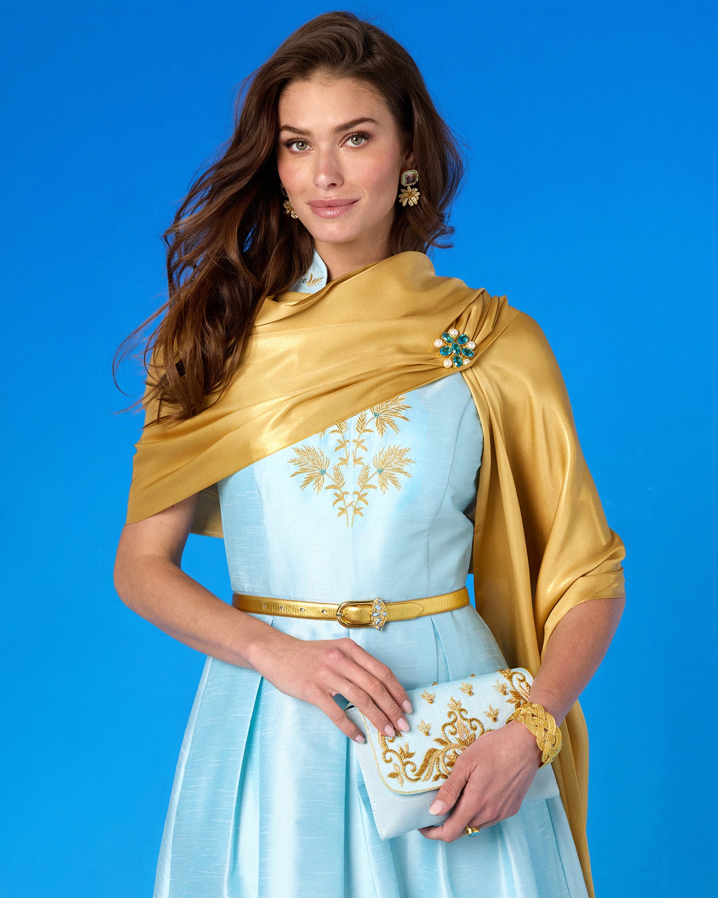 Woman in a light blue dress with gold accents against a blue background