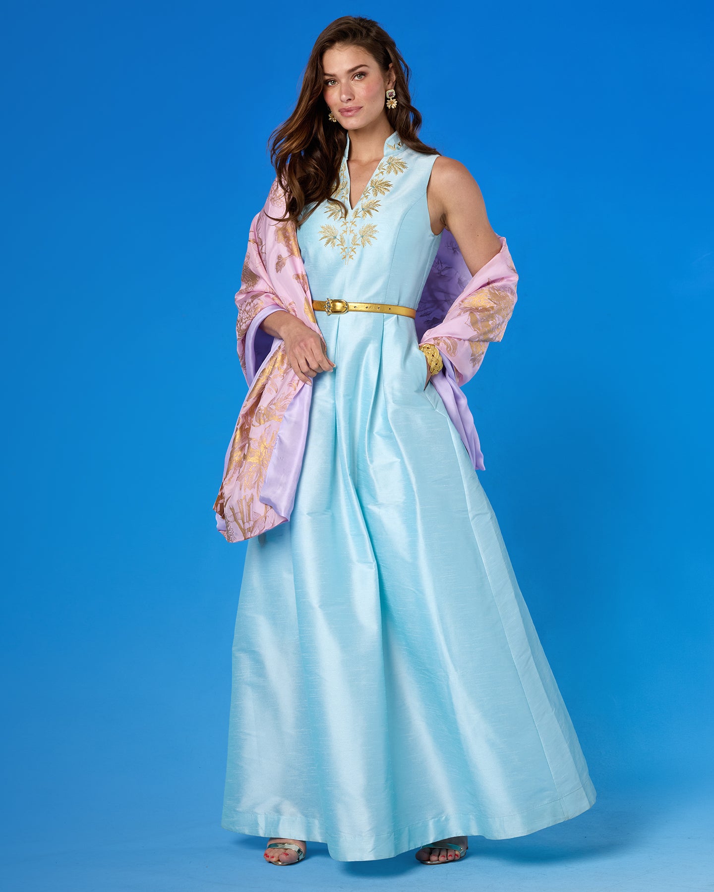 Woman wearing a light blue traditional outfit with a pink shawl against a blue background