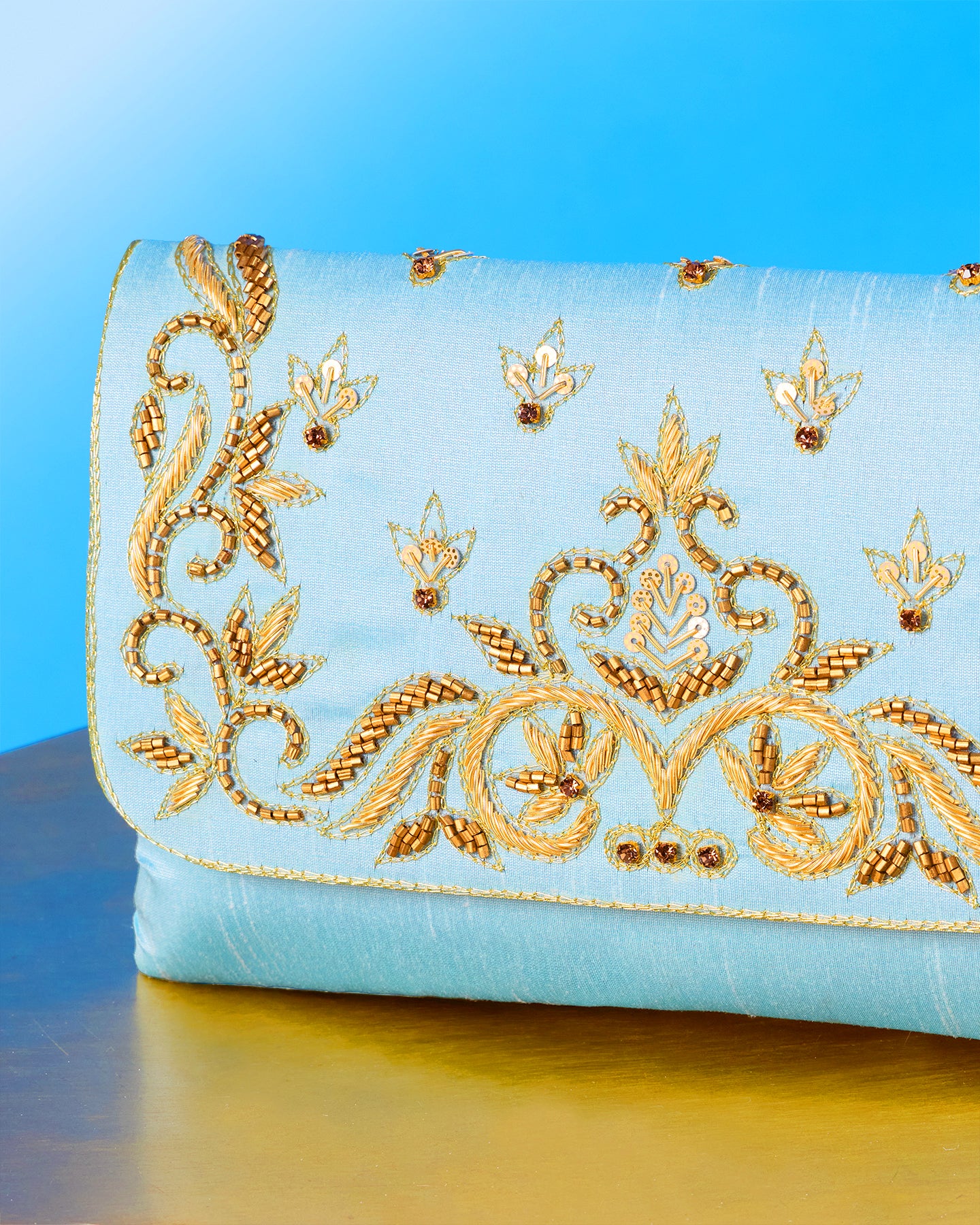 Decorative clutch with gold embroidery on a blue background