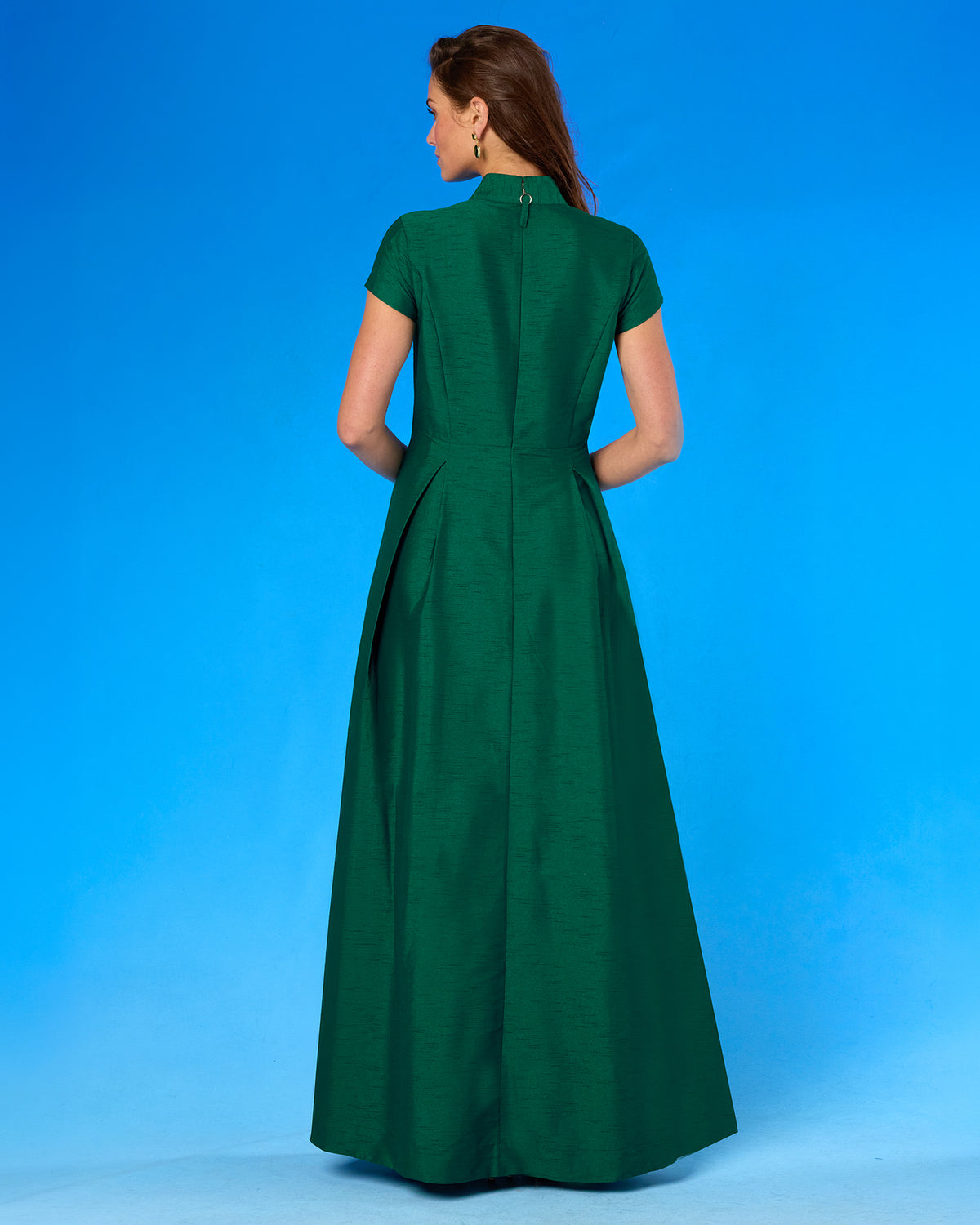 Back view of a woman wearing the Isabella Cap-Sleeve Gown in Emerald Green
