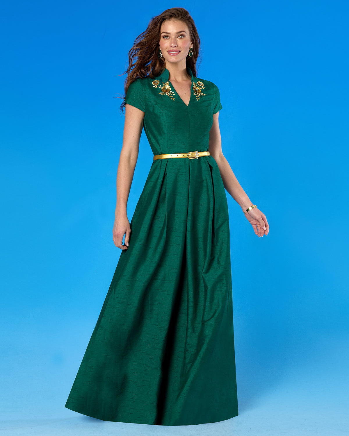 The Harlow Gold Leather Belt in Blue Gem Accents worn with the Isabella Cap-Sleeve Gown in Emerald Green