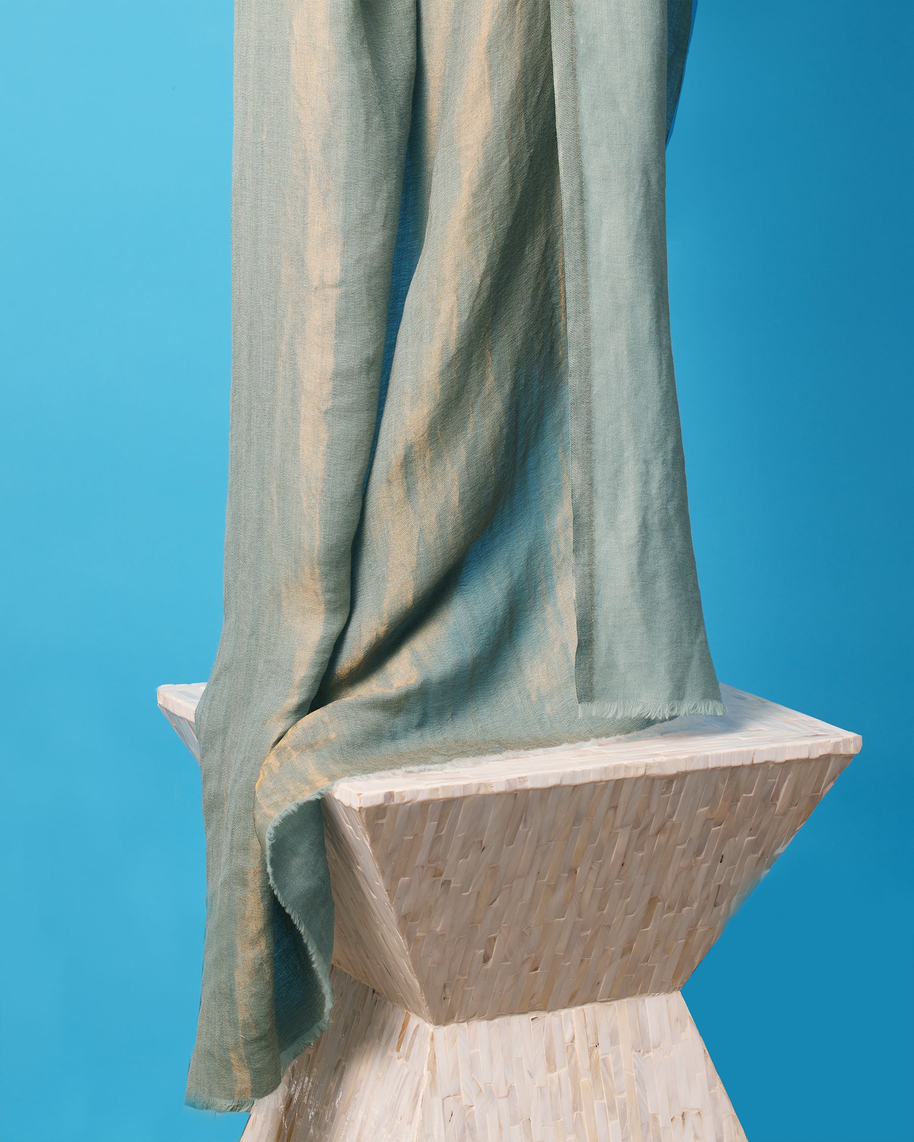 Josephine Reversible Pashmina Shawl in Gold Shimmer Teal-Against a blue backdrop