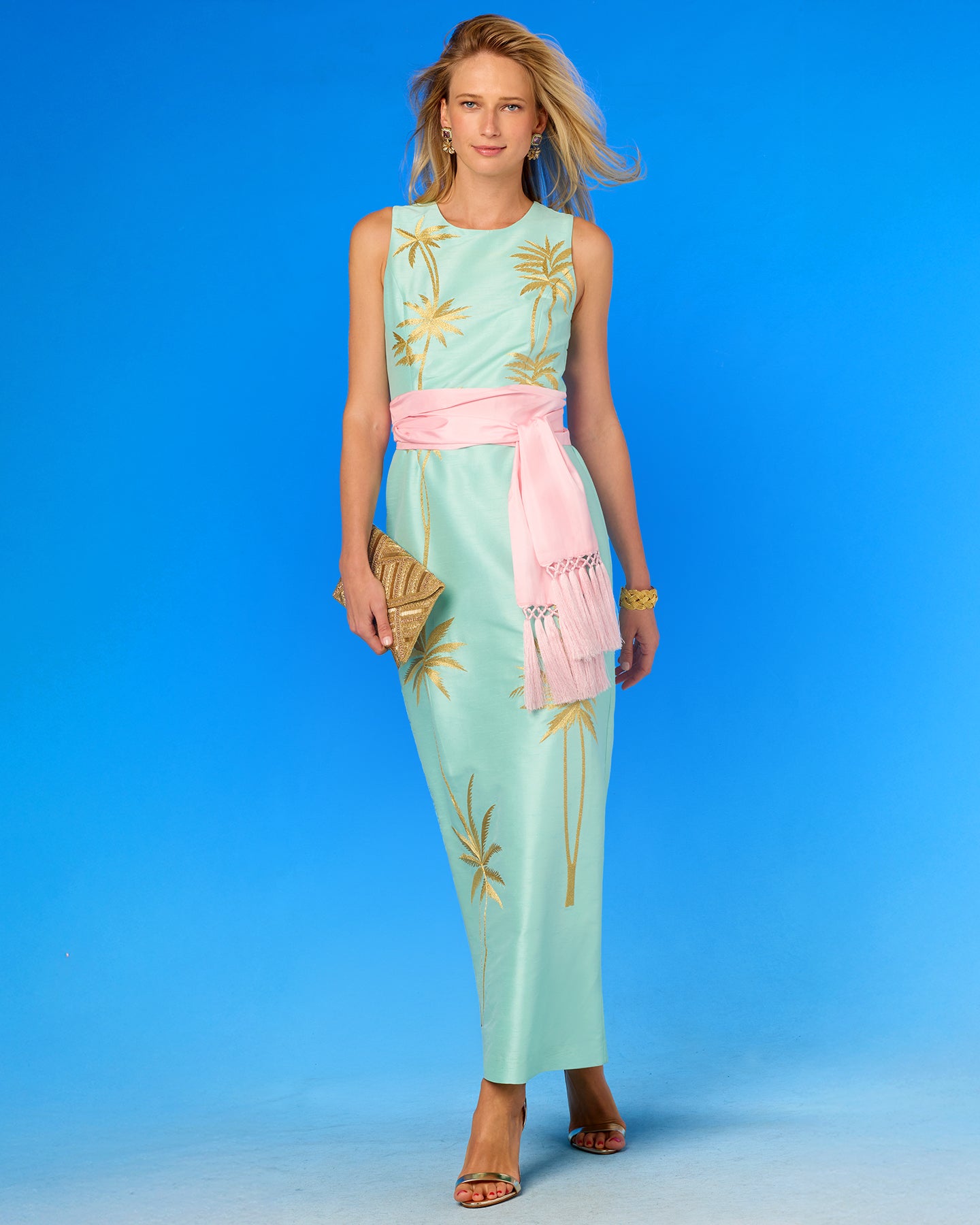 Woman wearing a light blue dress with palm tree patterns on a blue background
