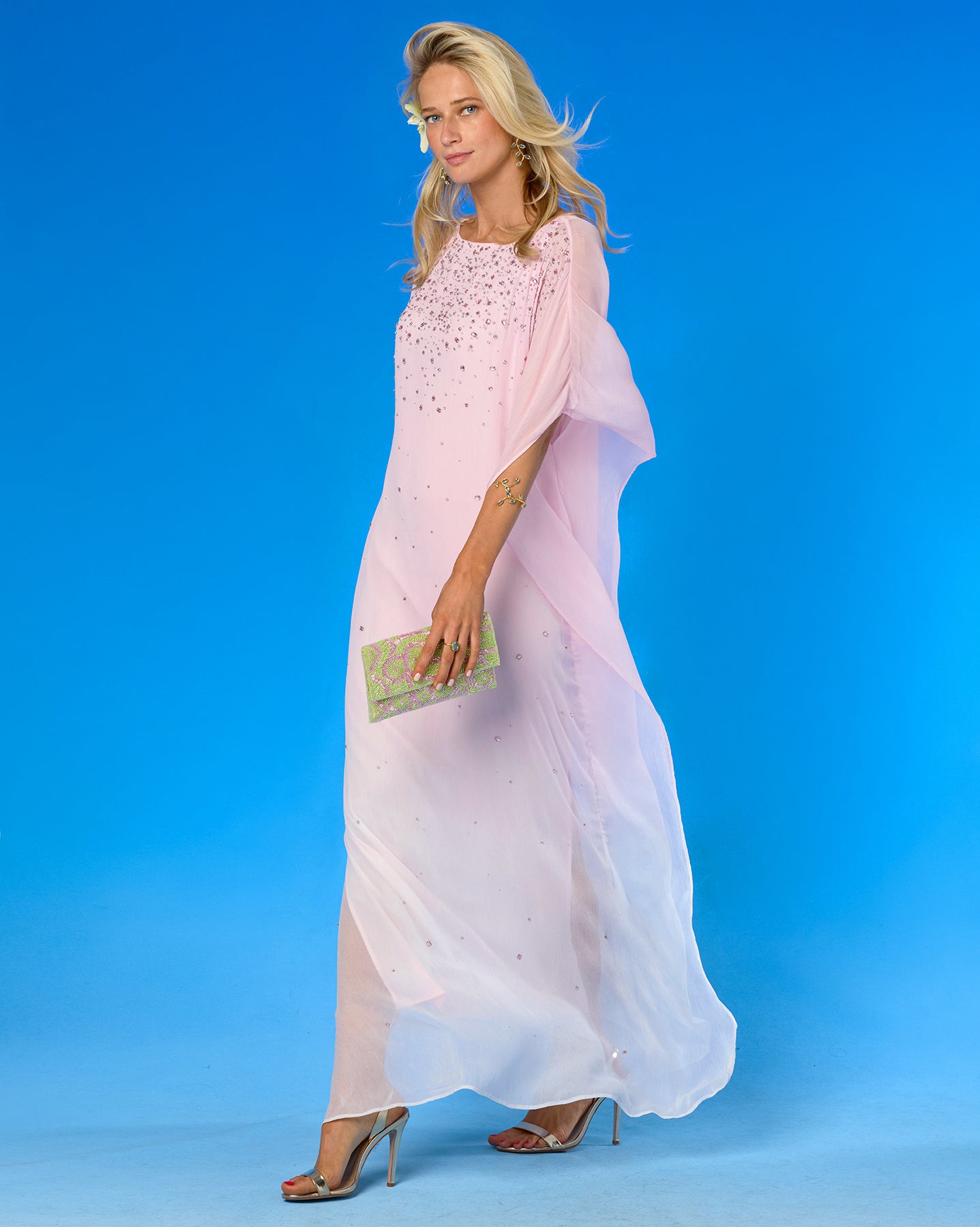 Woman wearing a pink dress with floral embellishments on a blue background