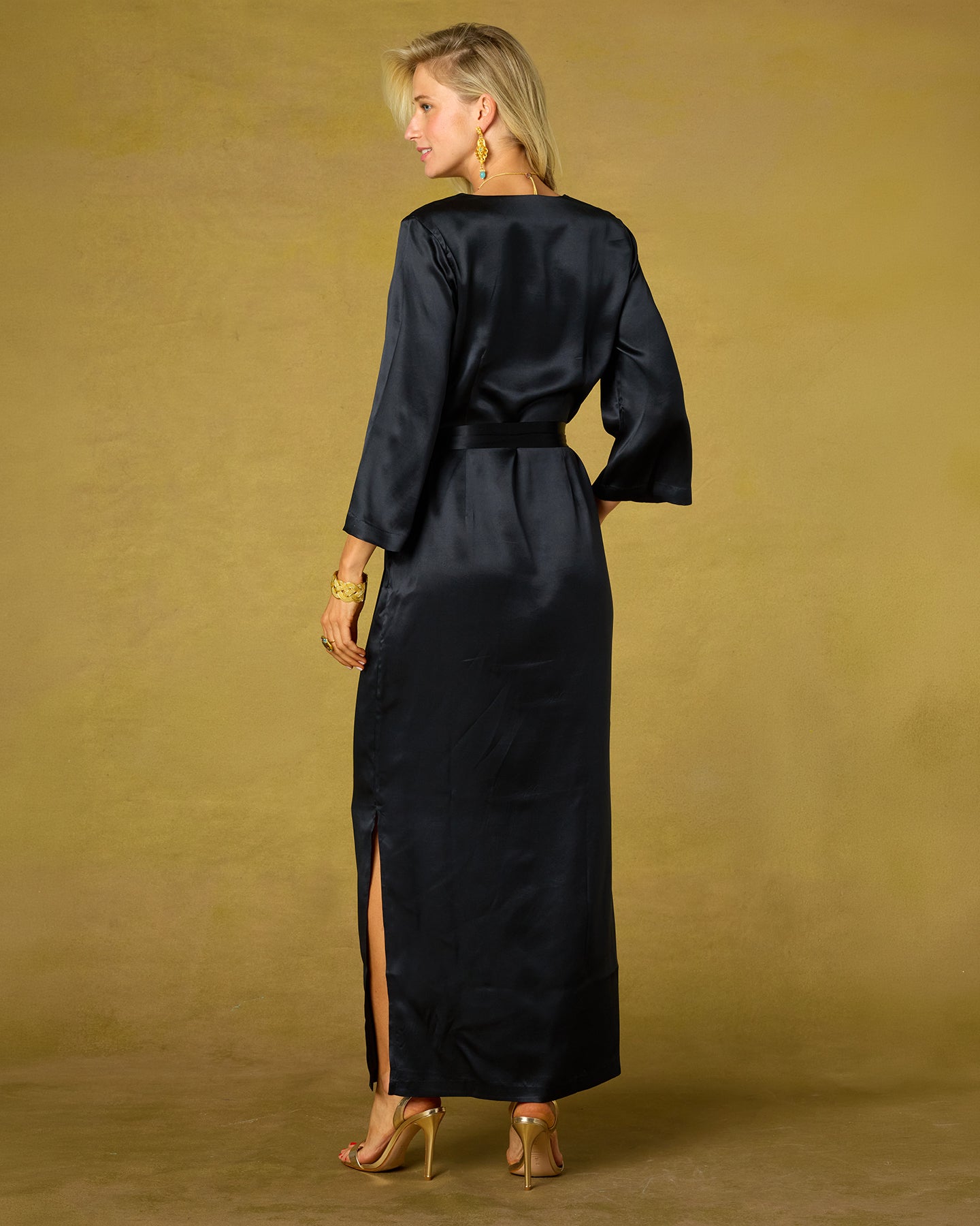 Woman wearing a black satin dress with a gold background