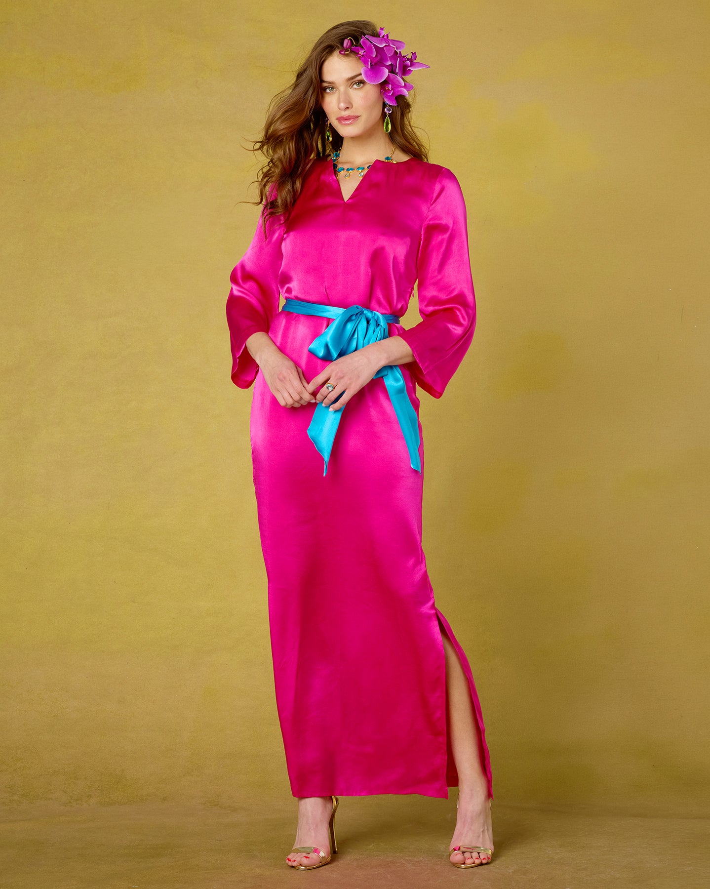 Woman wearing a bright pink dress with a blue belt against a yellow background