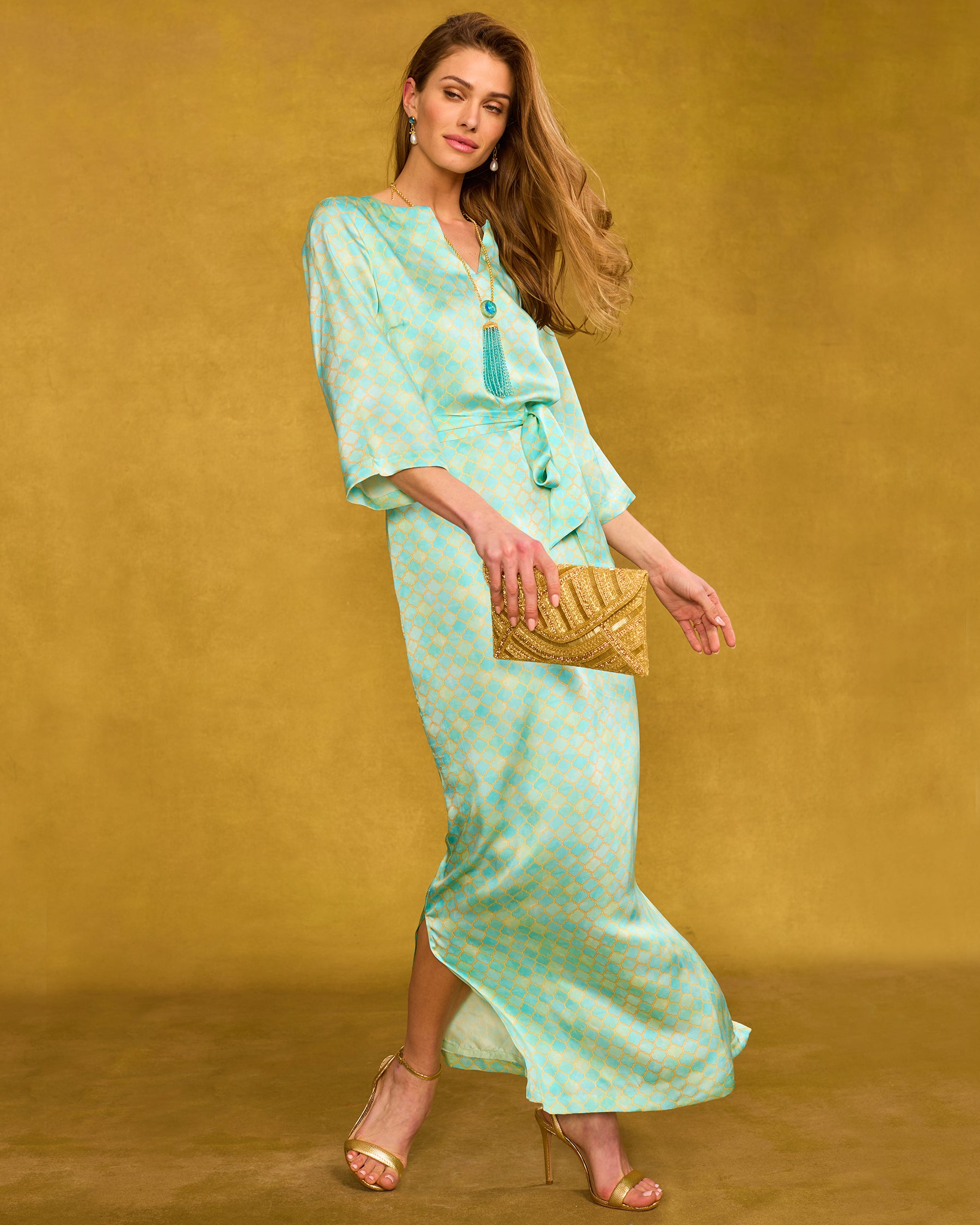 Majorelle Silk Dress in Mint Julep Alhambraside view walking and holding the Betty Beaded Gold Clutch