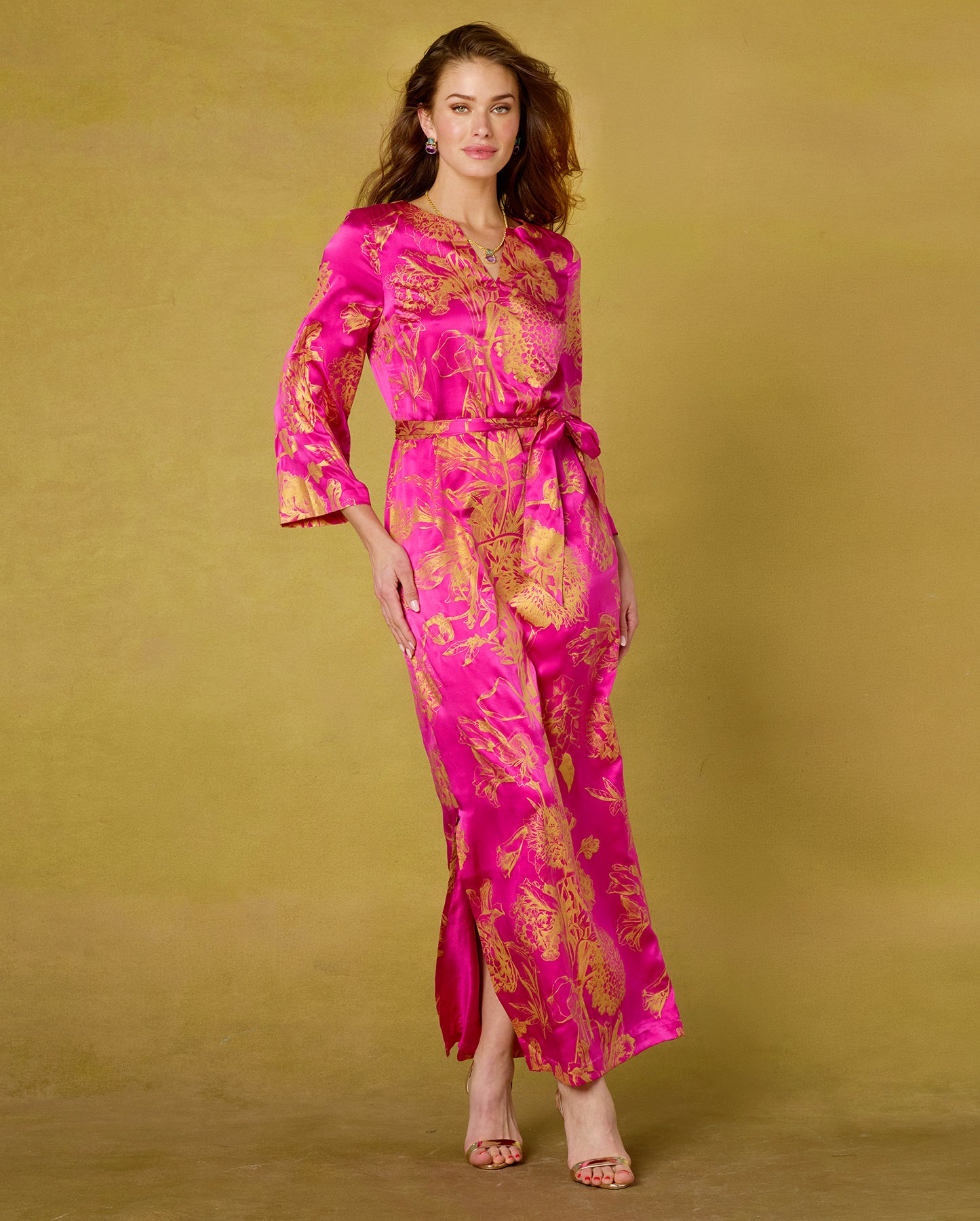 Woman wearing a pink and gold floral dress against a beige background