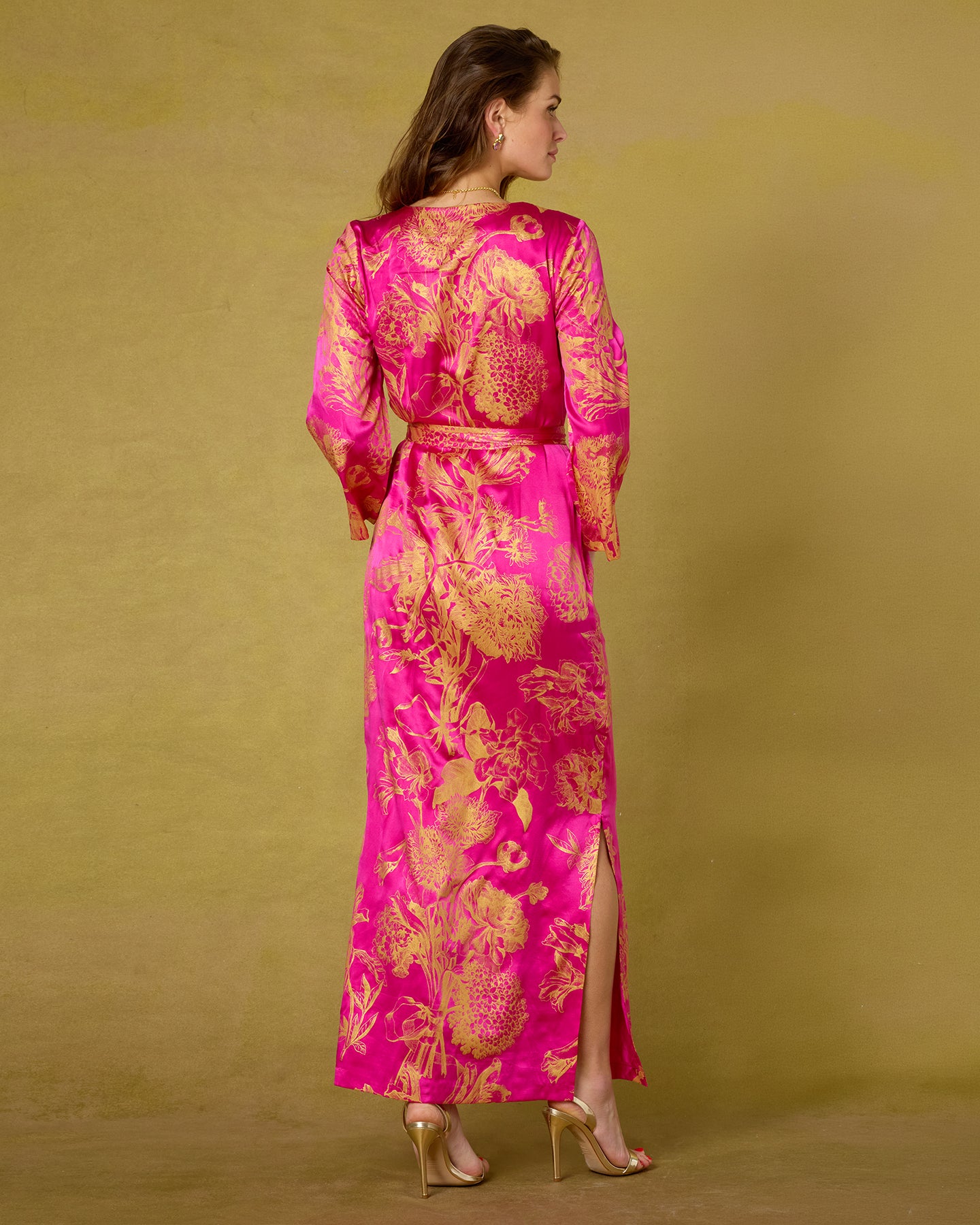 Woman wearing a pink and gold floral dress against a yellow background
