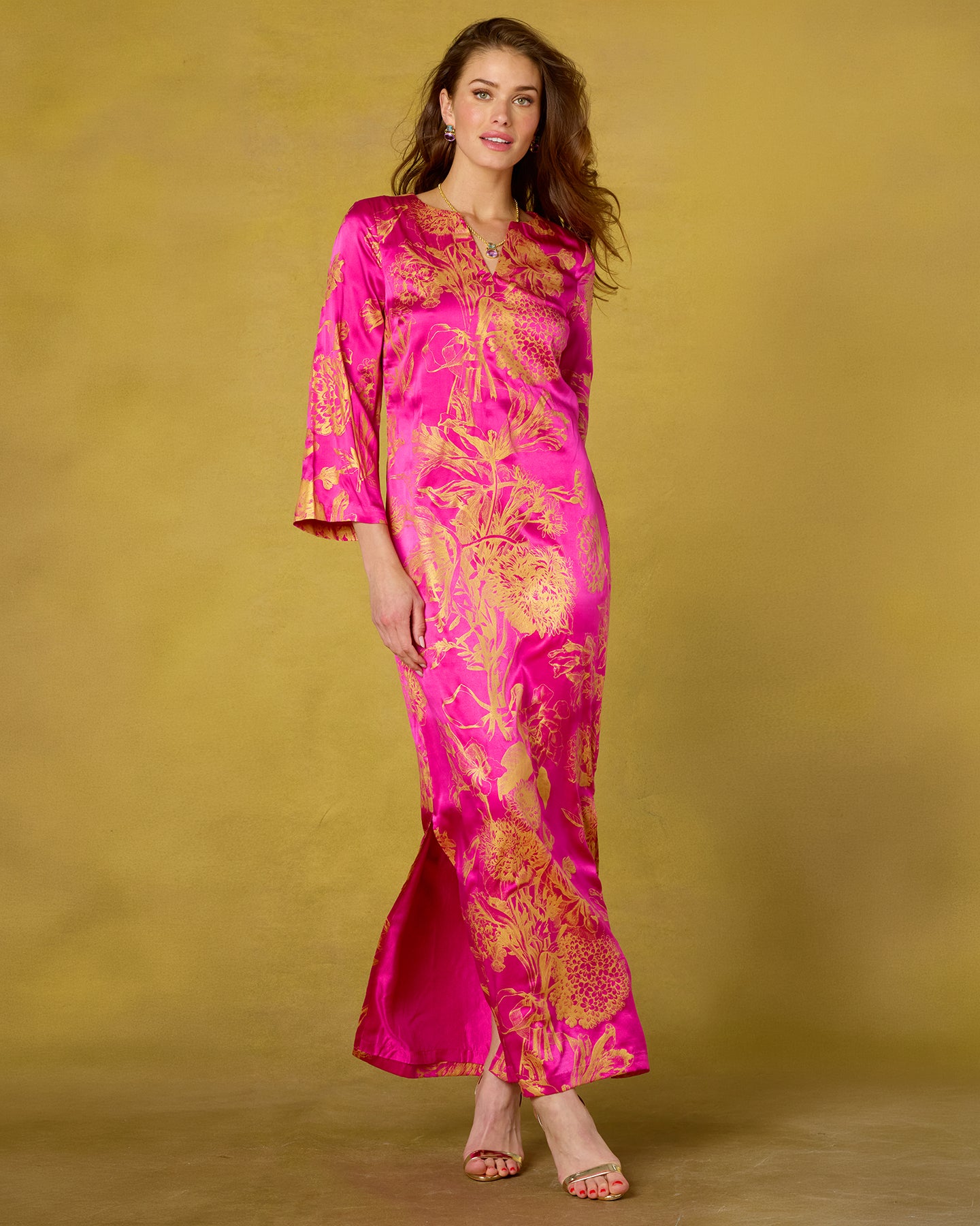 Woman wearing a pink and gold patterned dress against a beige background