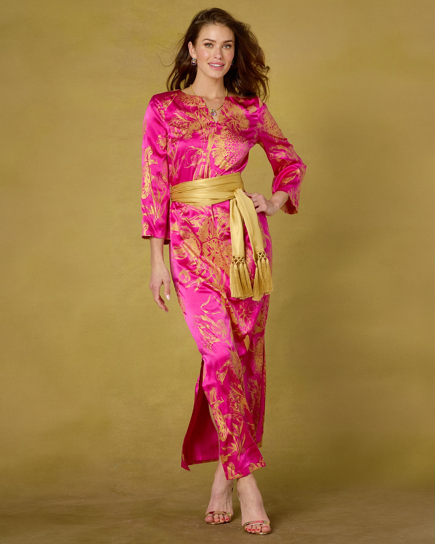 Woman wearing a pink and gold traditional outfit on a beige background