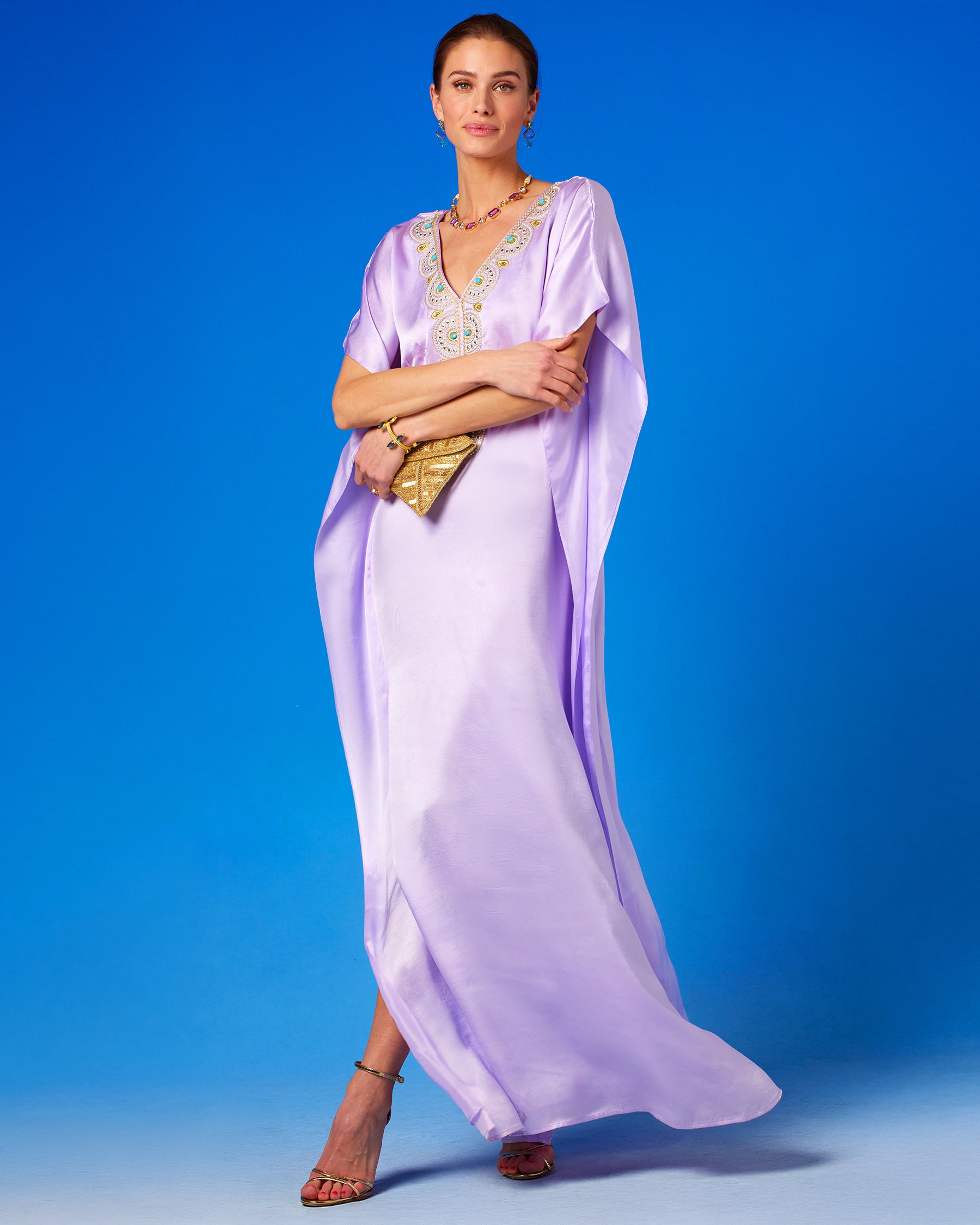 Noor Silk Kaftan in Lavender holding the Betty Gold Beaded Clutch