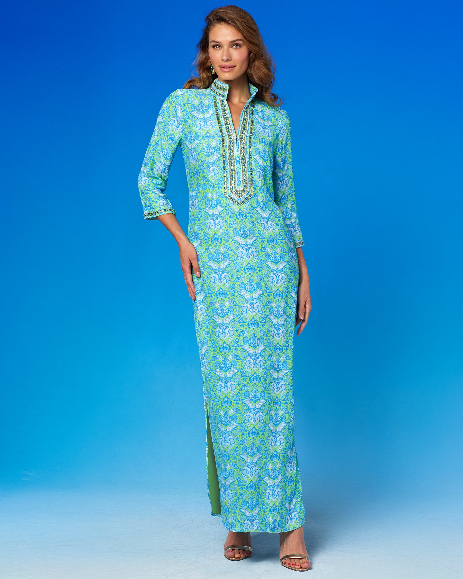 Woman wearing a long, patterned dress against a blue background