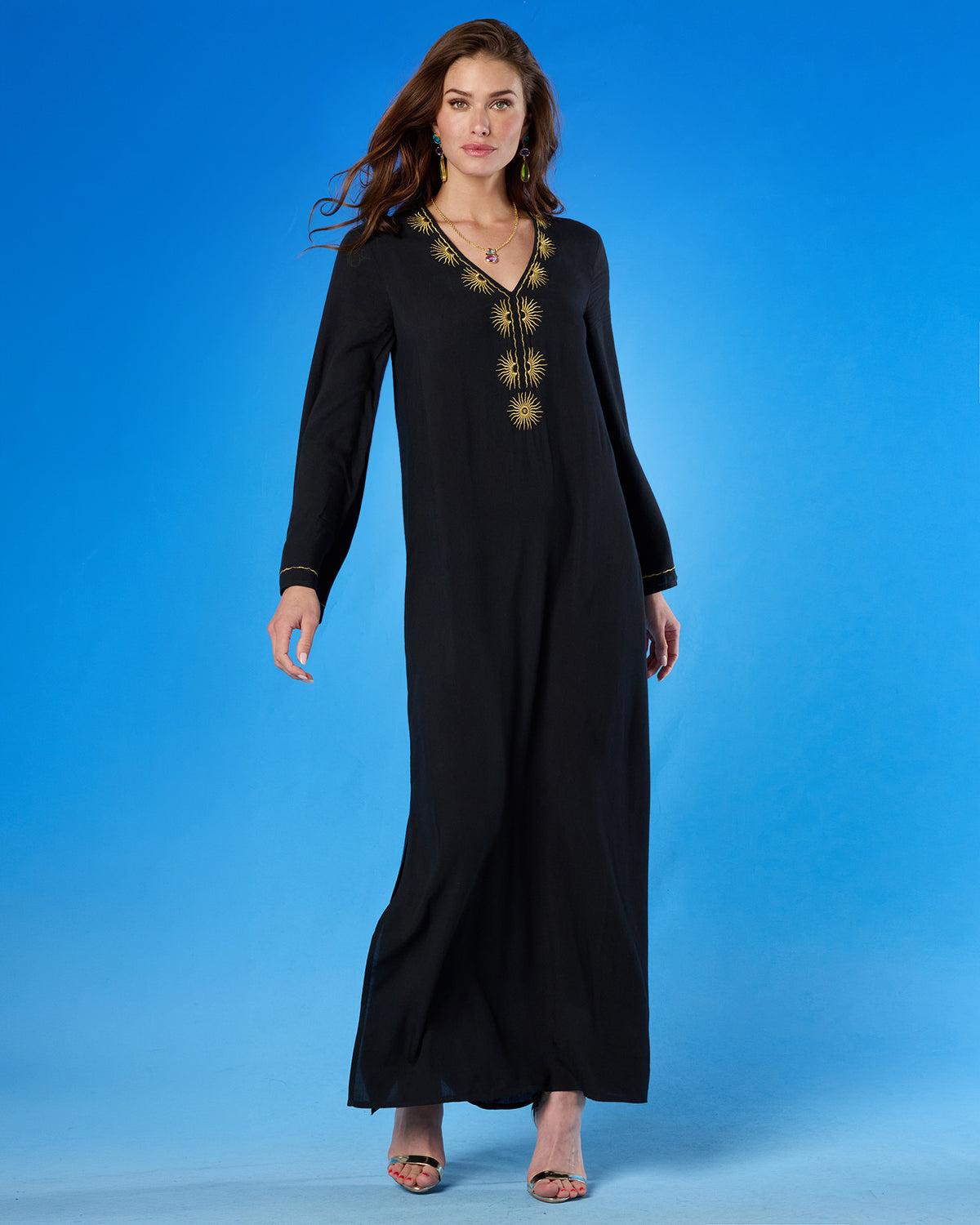 Woman wearing a black dress with gold embroidery on a blue background