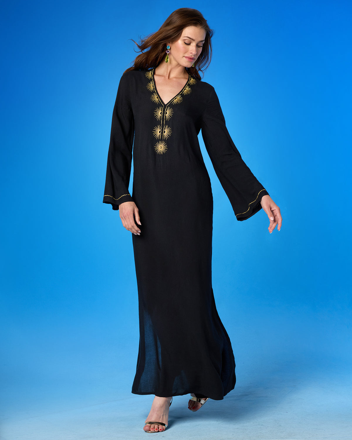 Woman wearing a black dress with gold embroidery on a blue background