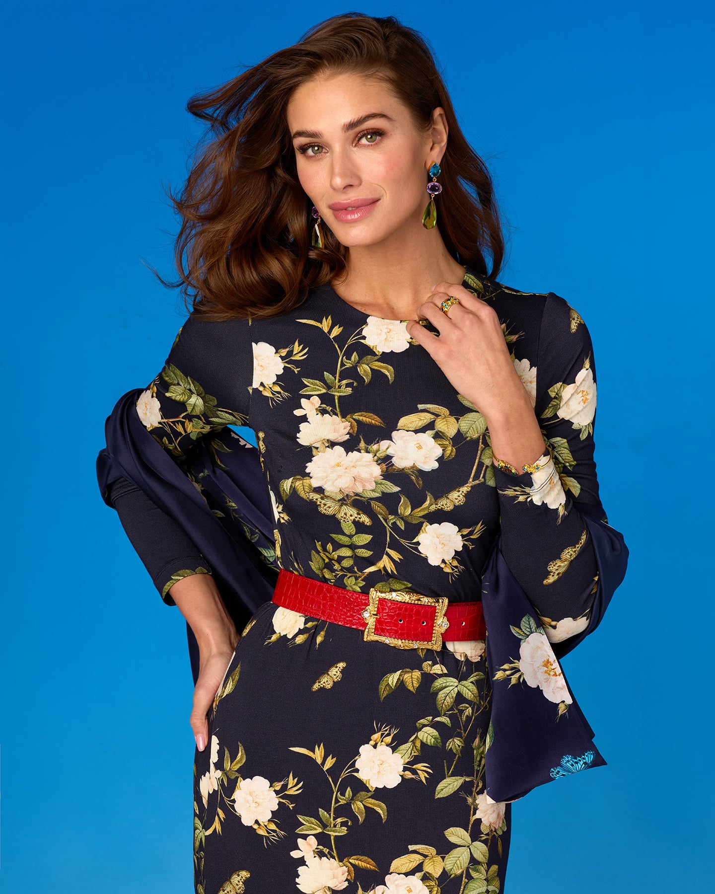 Woman wearing a floral dress with a red belt against a blue background