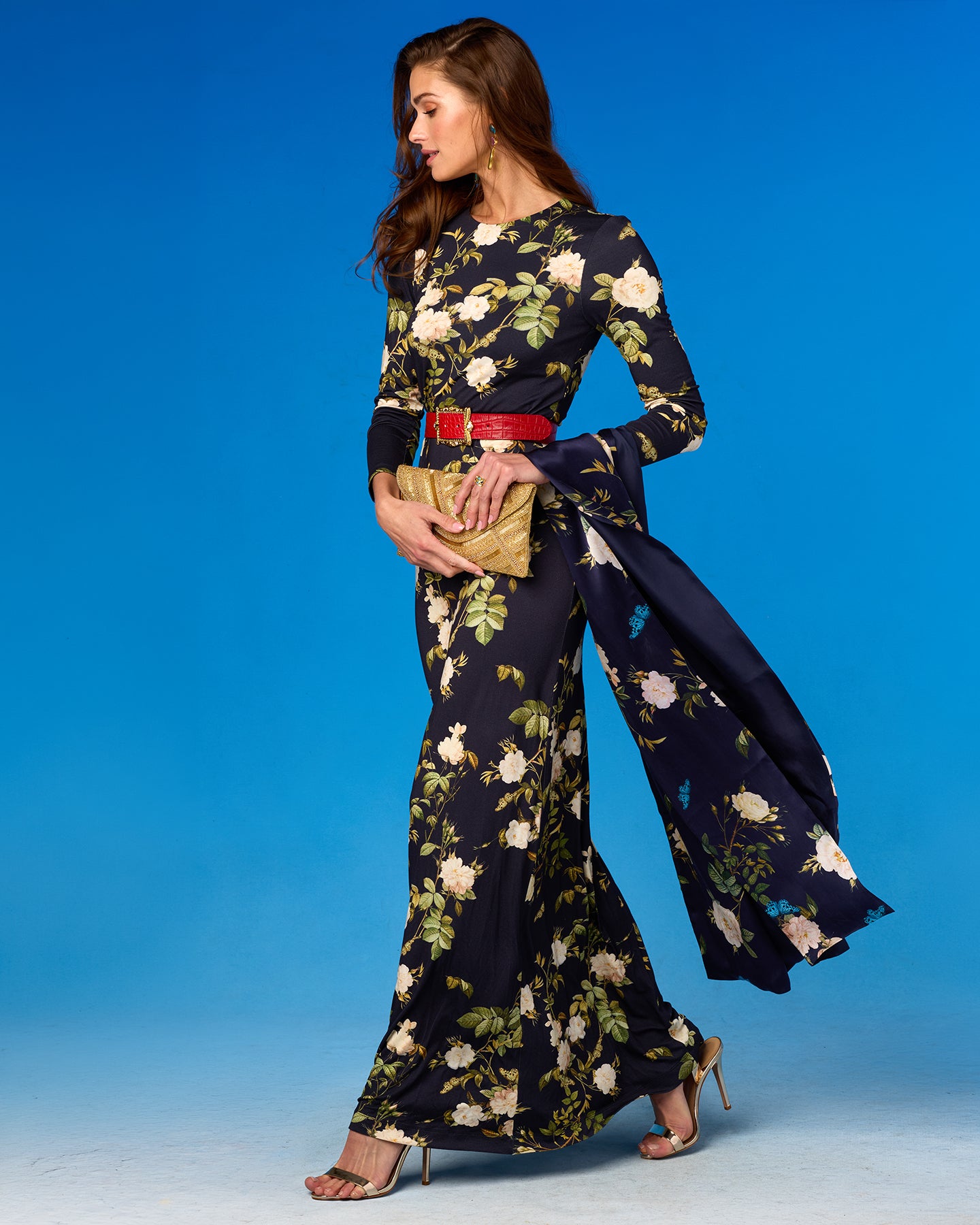 Woman wearing a floral dress with a red belt against a blue background