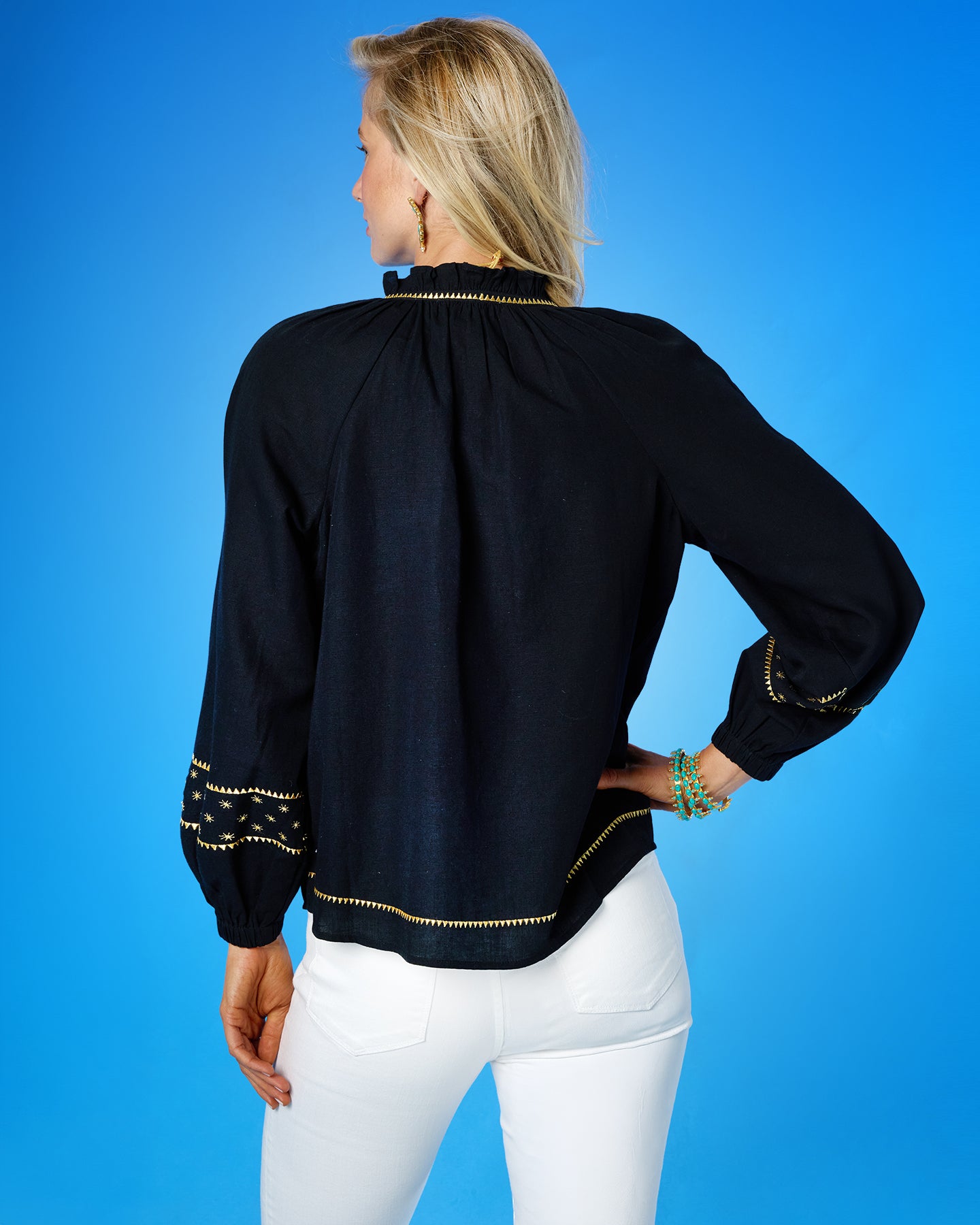 Woman wearing a black blouse with gold trim on a blue background
