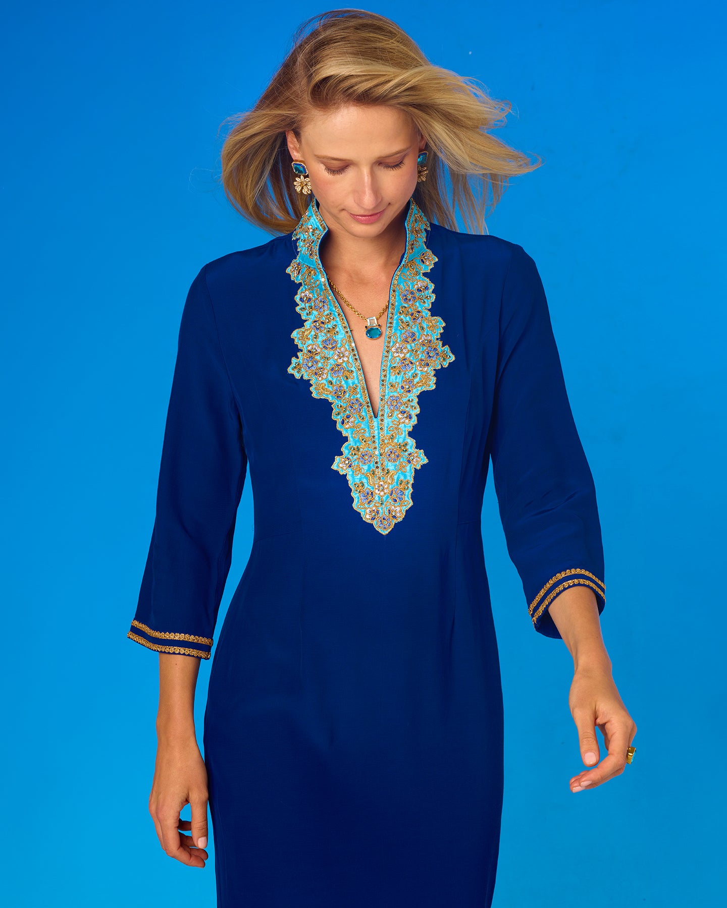 Woman wearing a blue dress with intricate lace detailing on a blue background