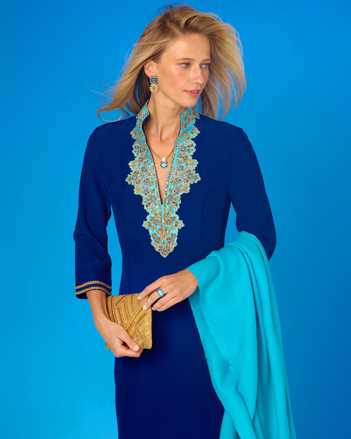 Woman in a blue dress with intricate detailing against a blue background