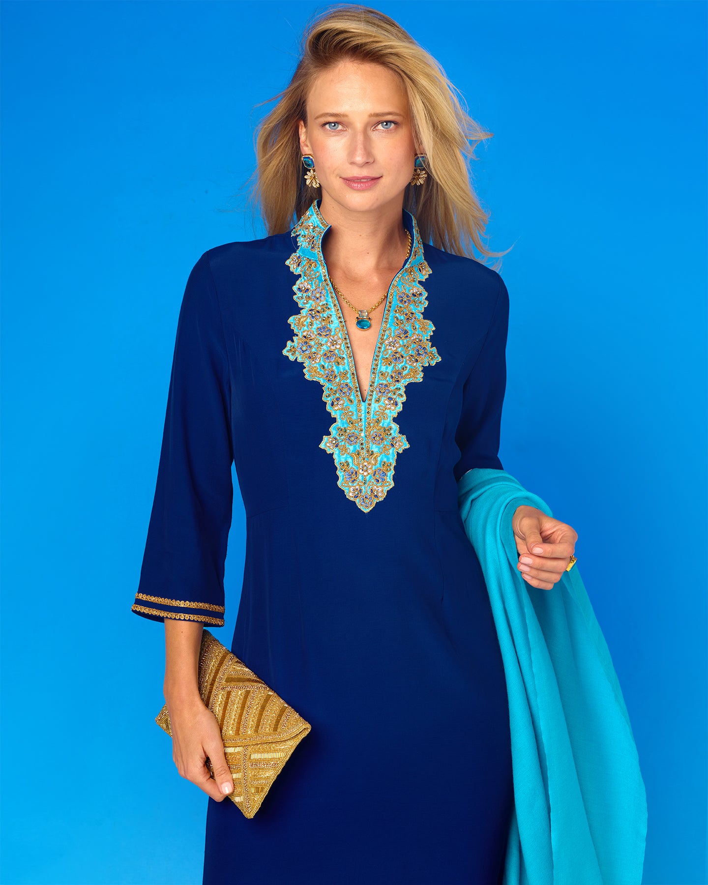 Woman wearing a blue dress with intricate embroidery against a blue background