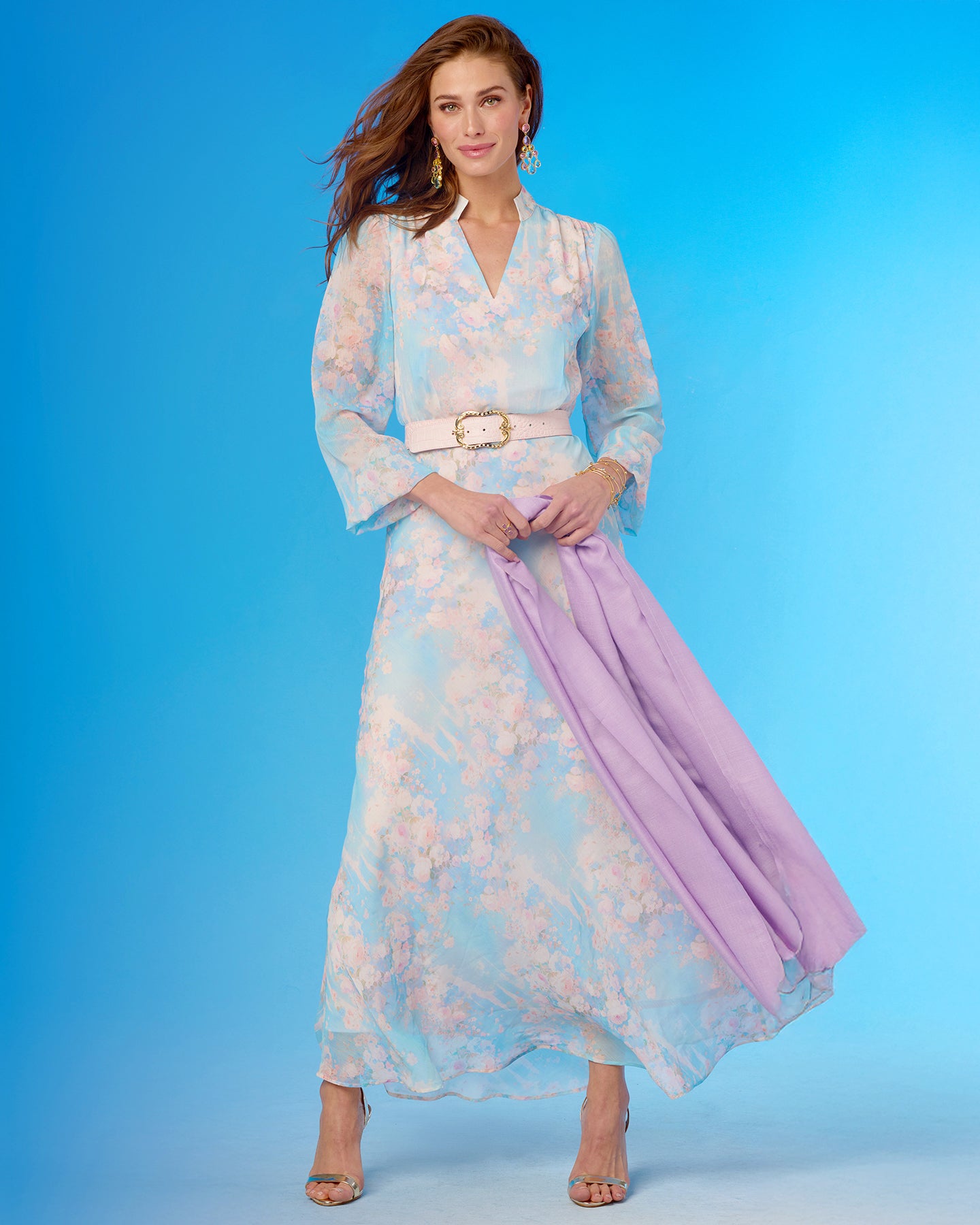 Woman wearing a floral dress with a purple scarf against a blue background
