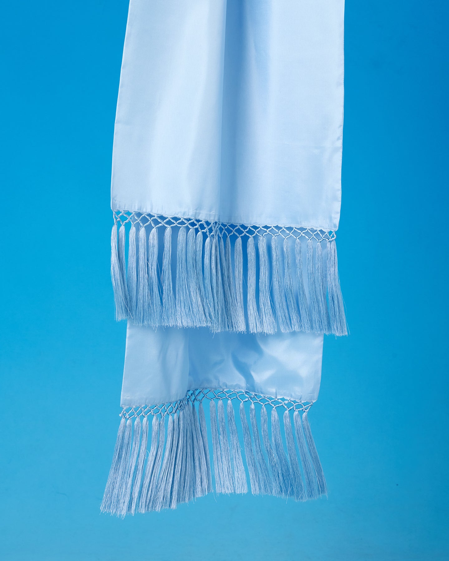 Light blue scarf with fringe details on a solid blue background