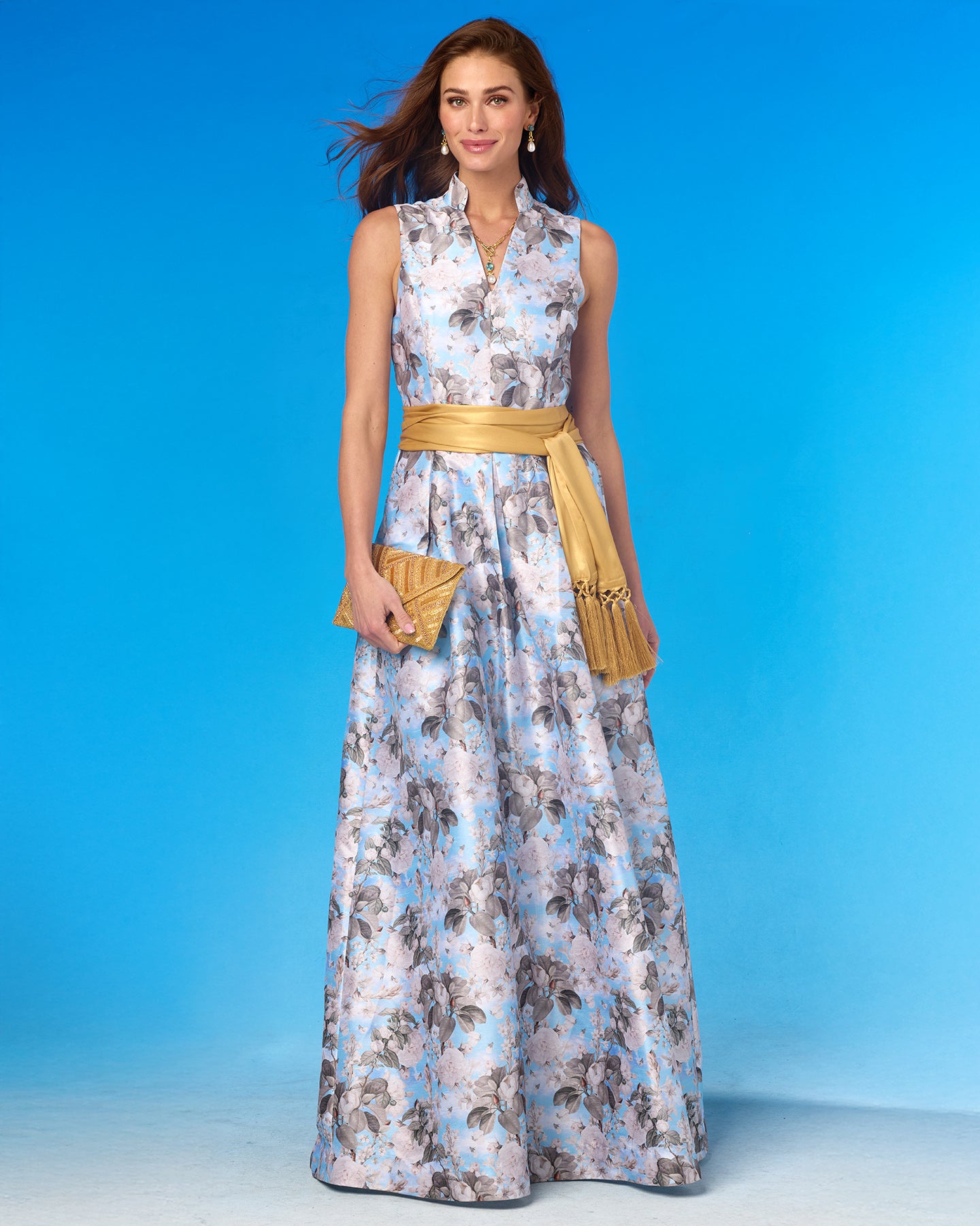 Woman wearing a floral dress with a gold belt against a blue background