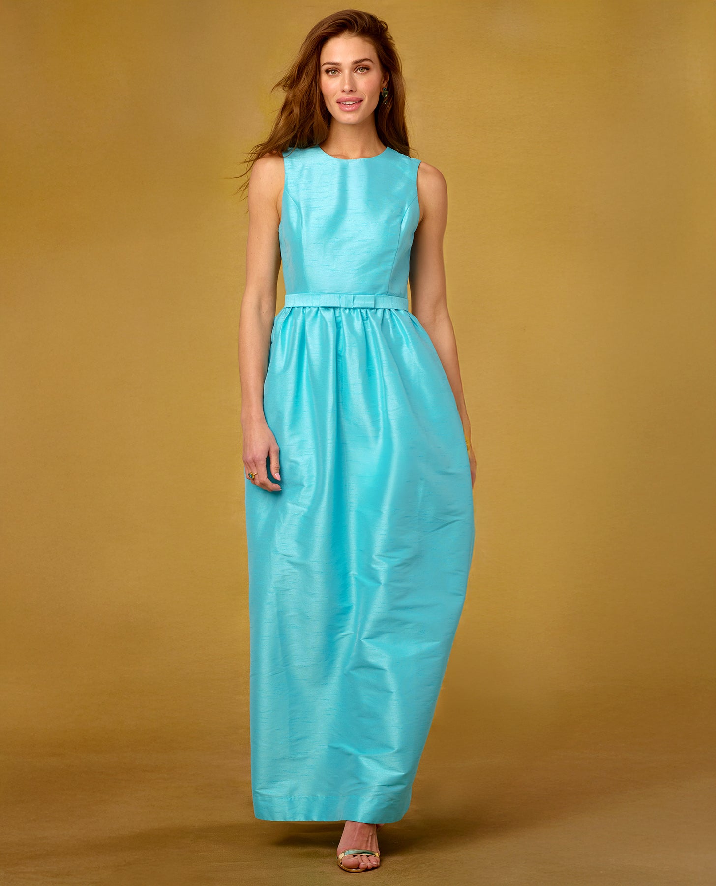 Woman wearing a turquoise dress against a beige background