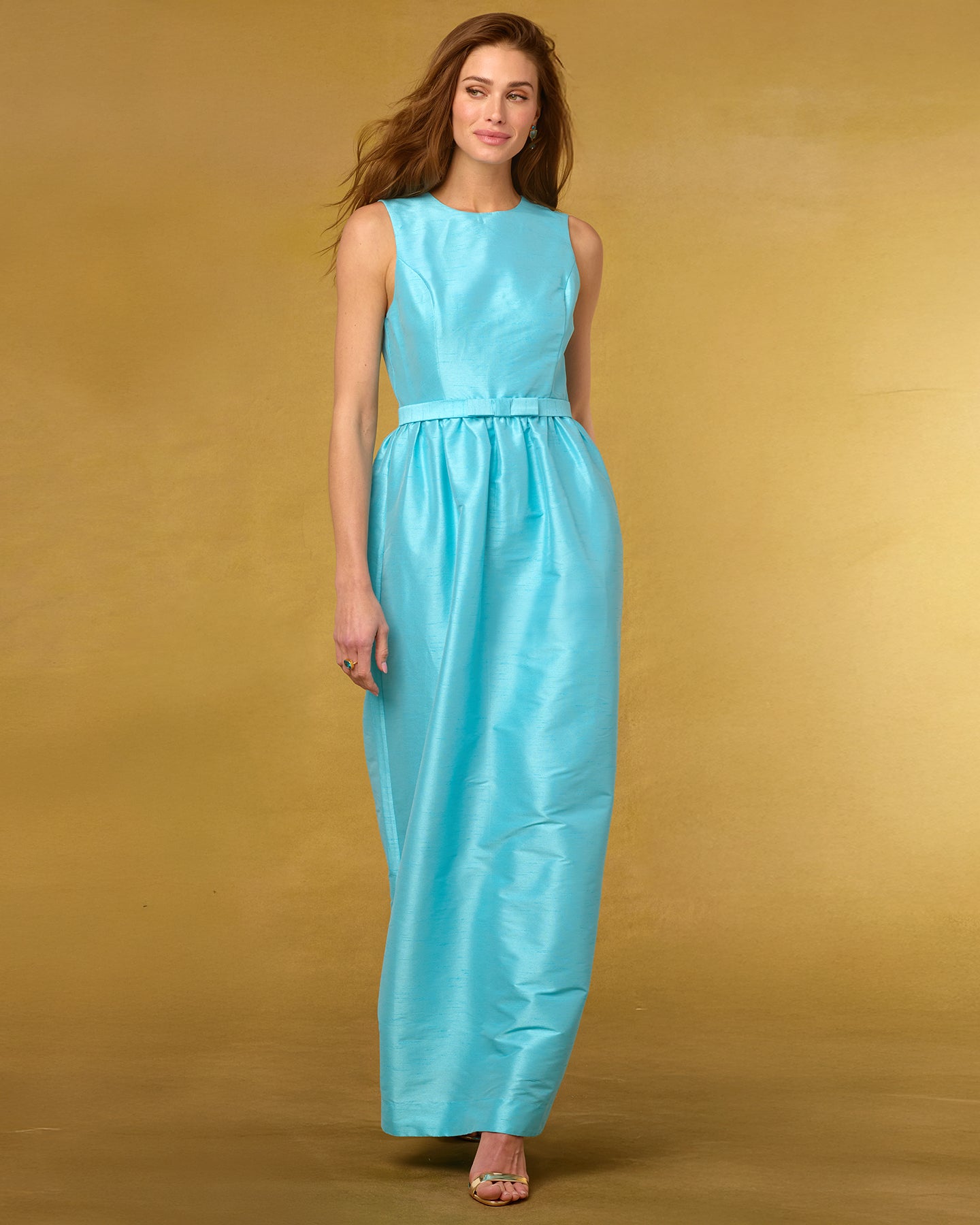 Woman wearing a robin egg blue dress against a gold background.