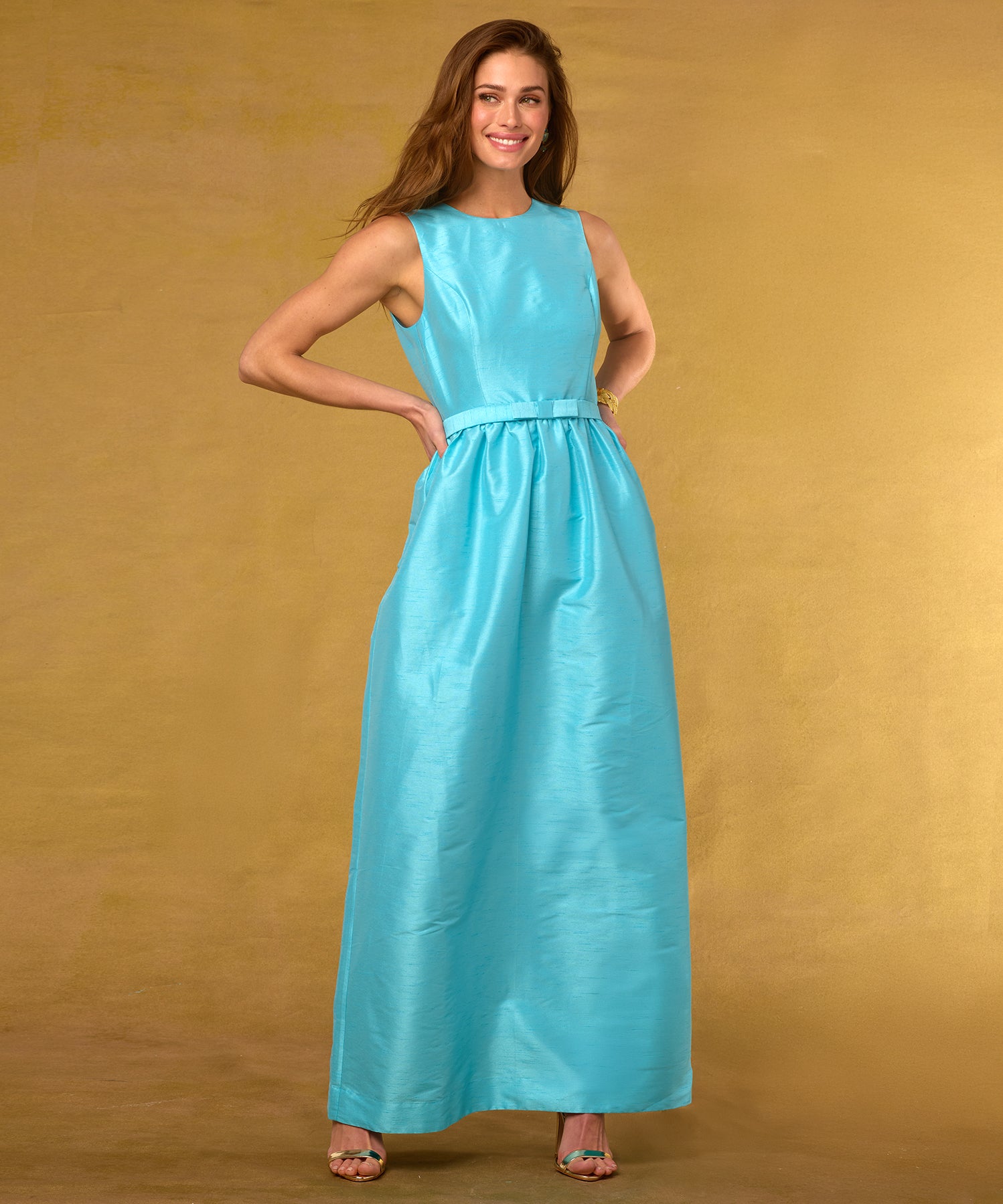 Woman wearing a turquoise dress against a gold background