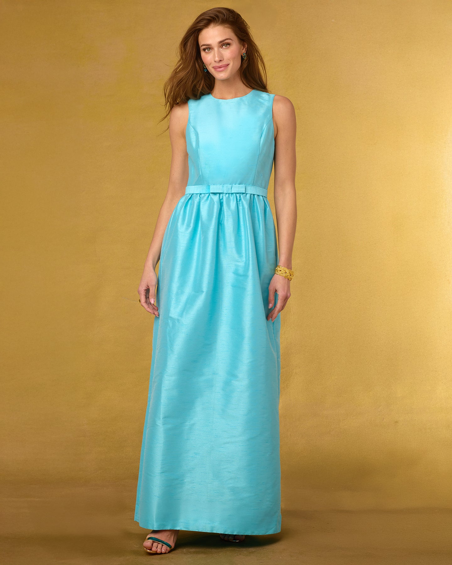 Woman wearing a turquoise dress against a gold background