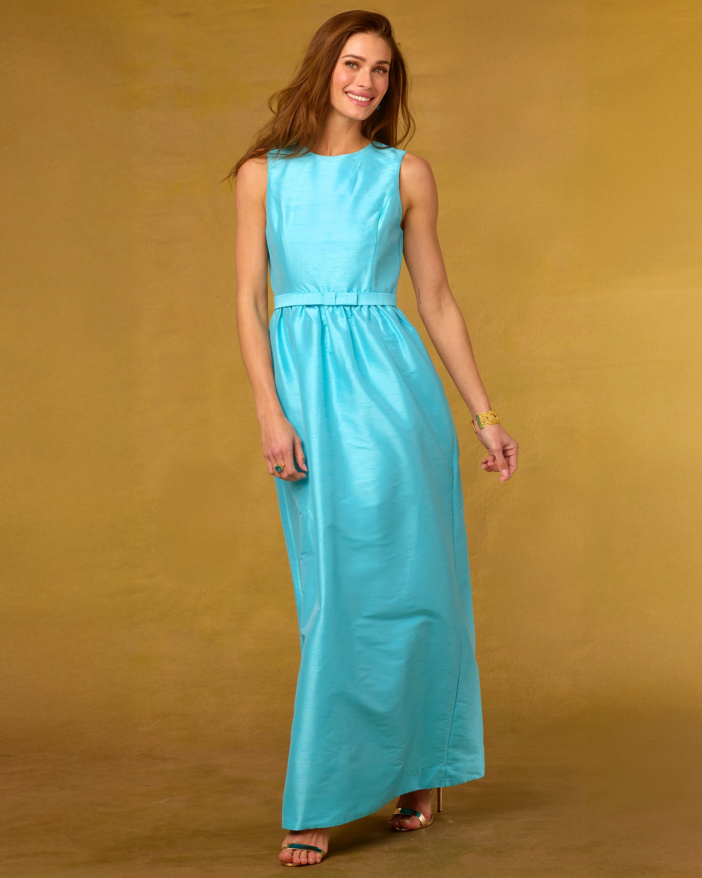 Woman wearing a turquoise dress against a gold background