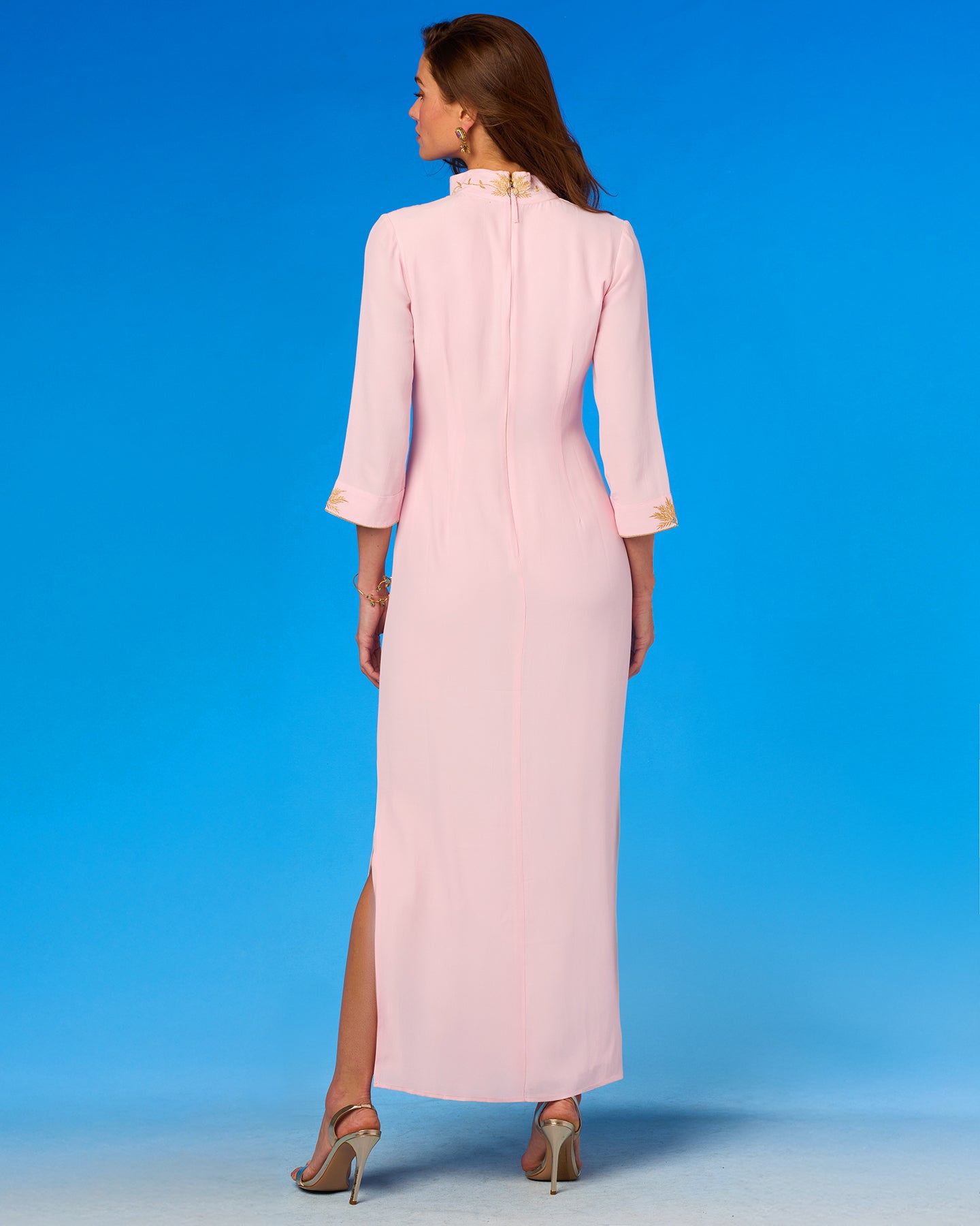 Woman wearing a light pink dress with a high slit on a blue background
