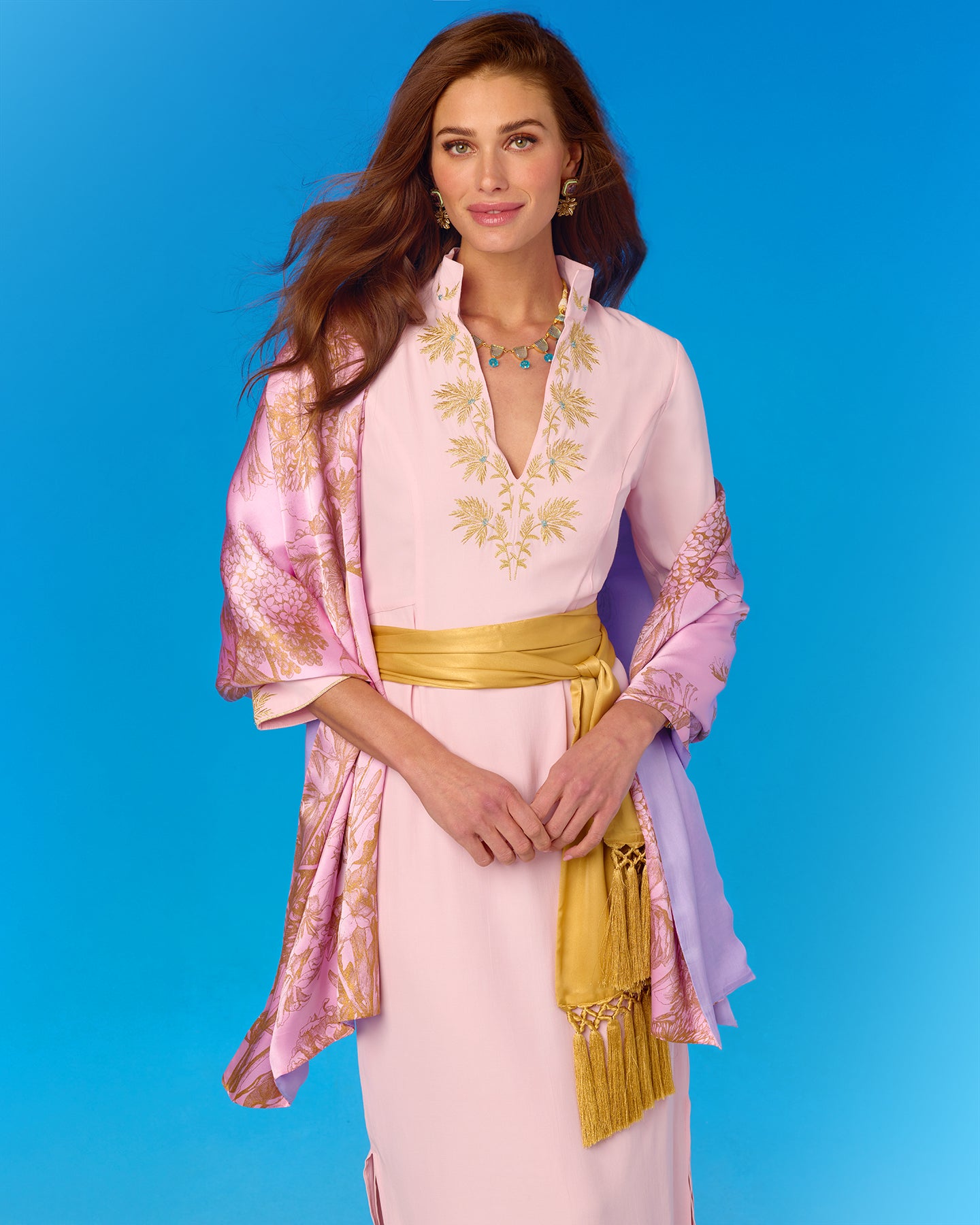 Woman wearing a pink and gold outfit with a blue background