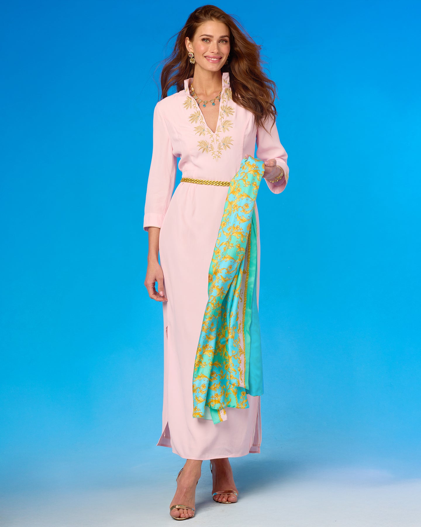 Woman in a pink outfit with a green and yellow scarf against a blue background