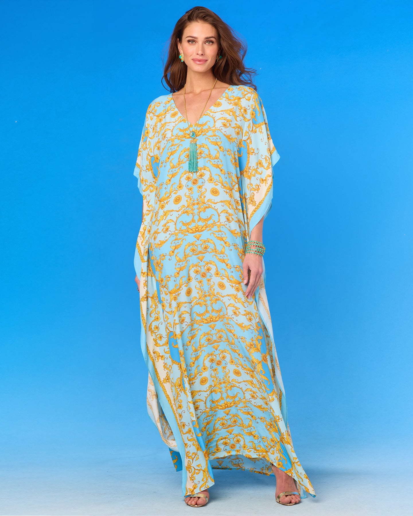 Woman wearing a long, light blue and yellow patterned dress against a blue background