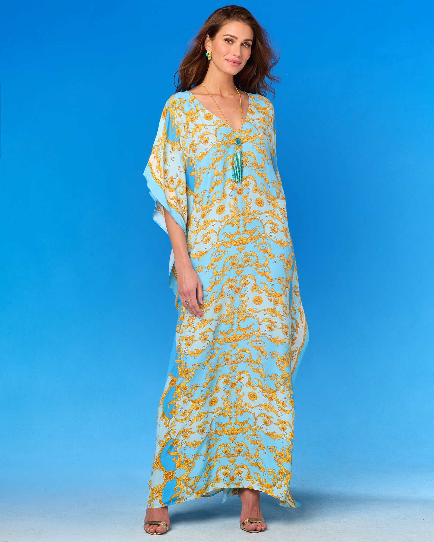 Woman wearing a long, patterned dress against a blue background