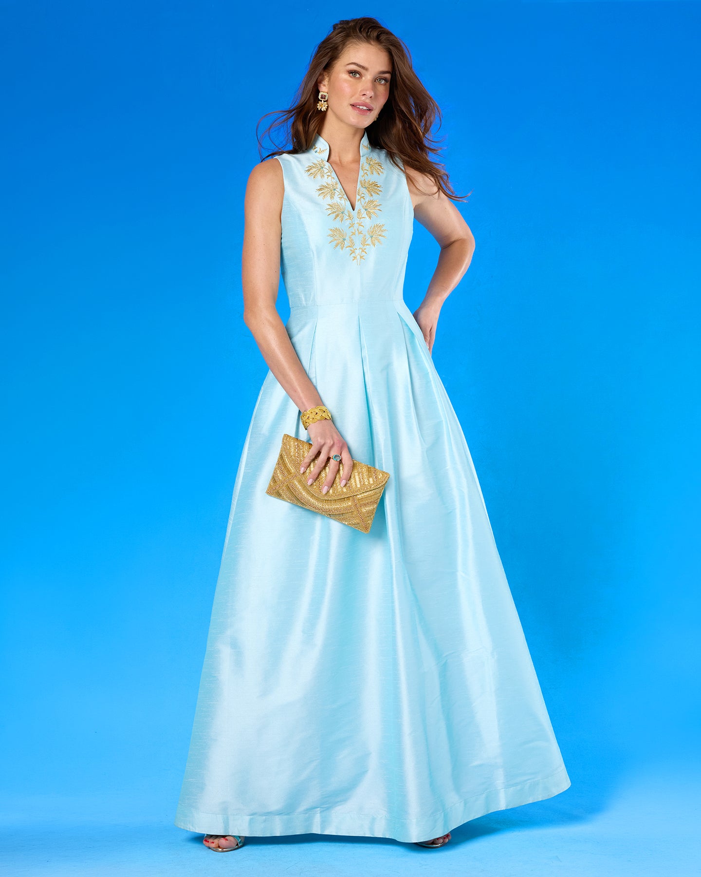 The Betty Clutch in Beaded Gold worn with the Celestine Gown in Pastel Blue and Gold Palm Embroidery